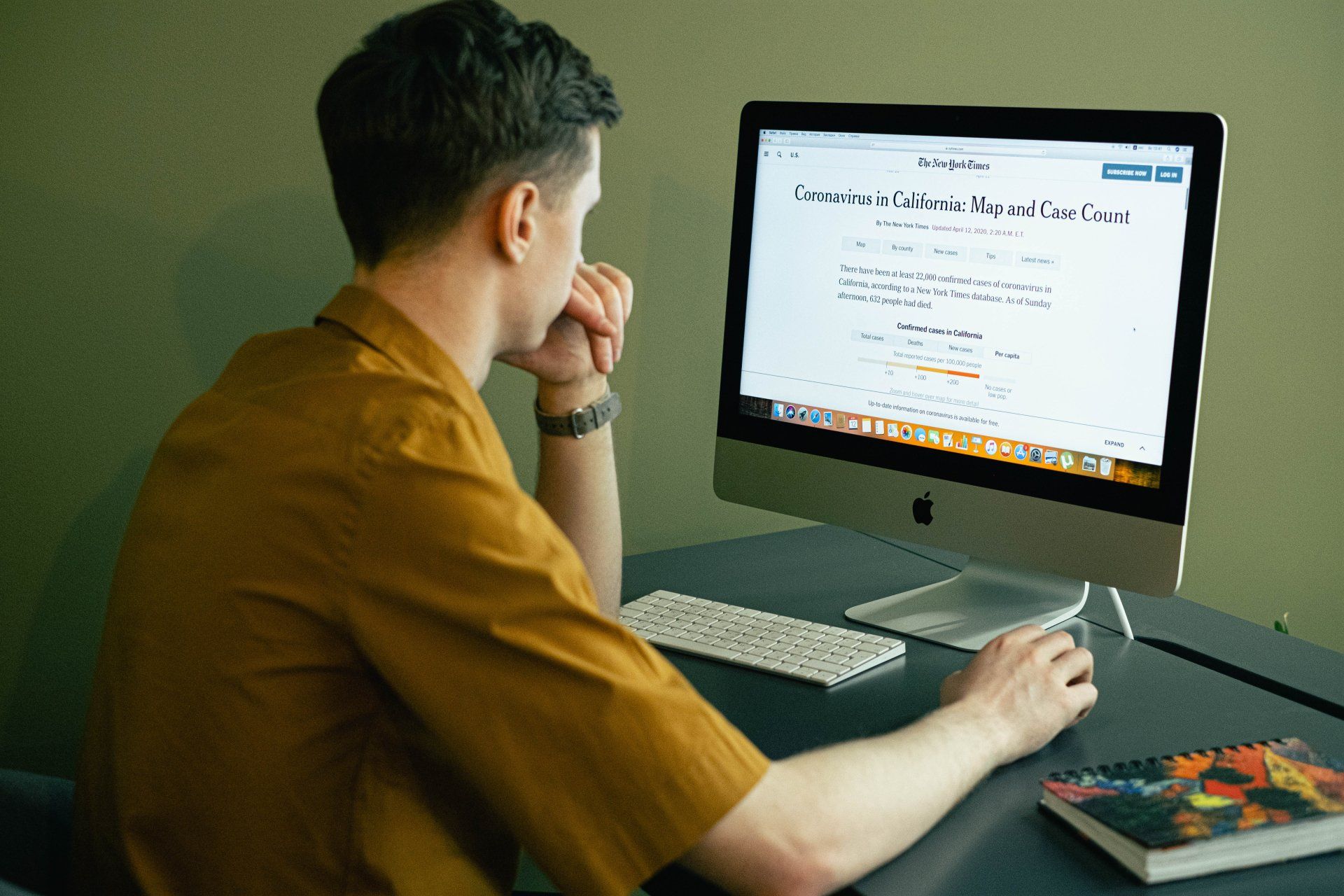 A man is sitting at a desk looking at a computer screen.