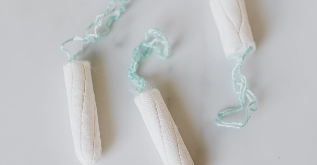 Three white tampons with teal strings, on a white surface.
