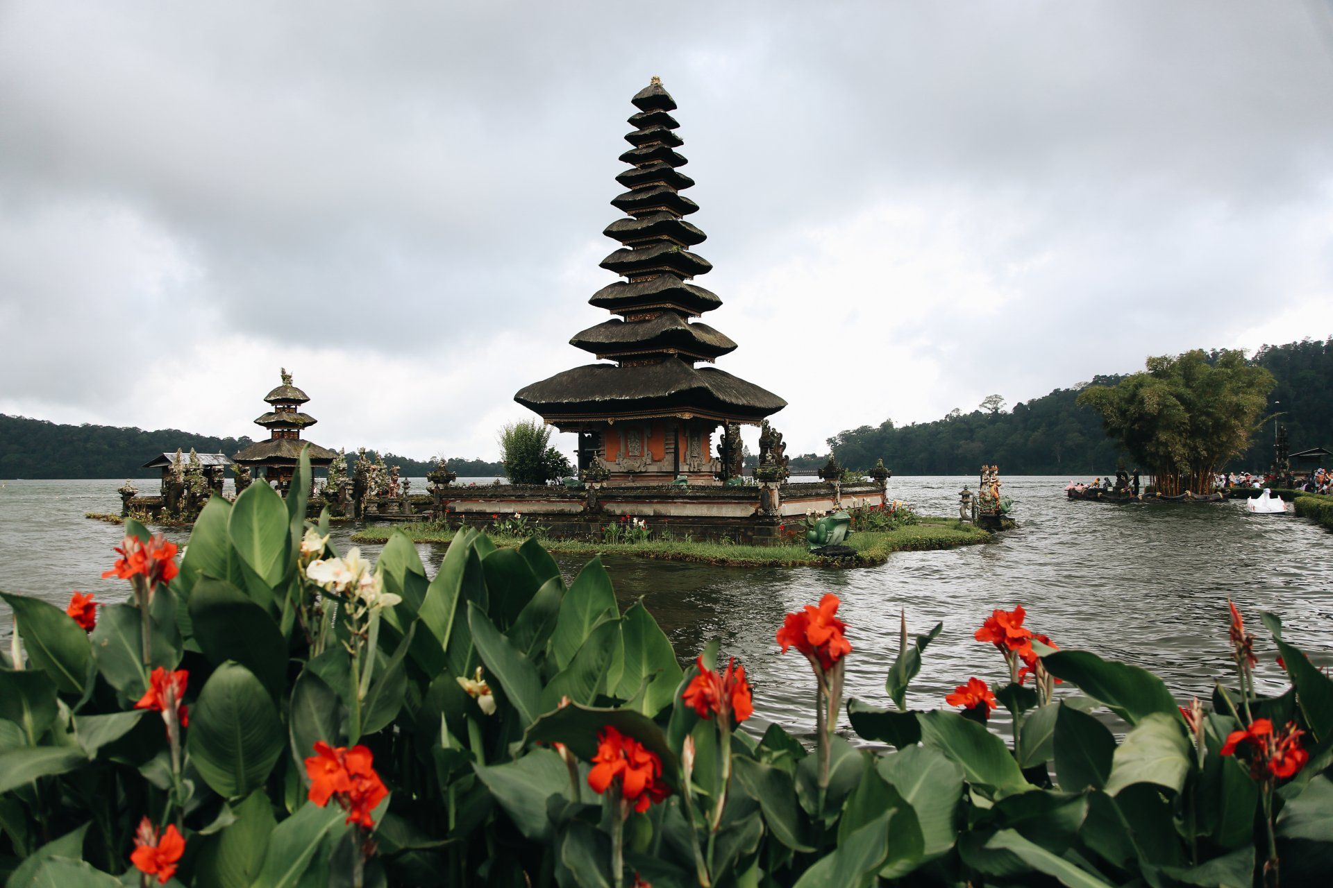 A temple on a small island in the middle of a lake surrounded by flowers.