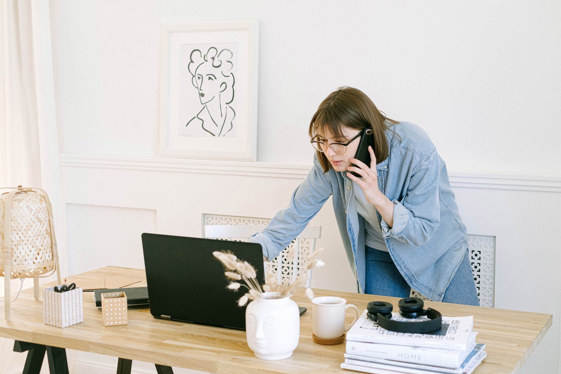 A woman is talking on a cell phone in front of a laptop computer.
