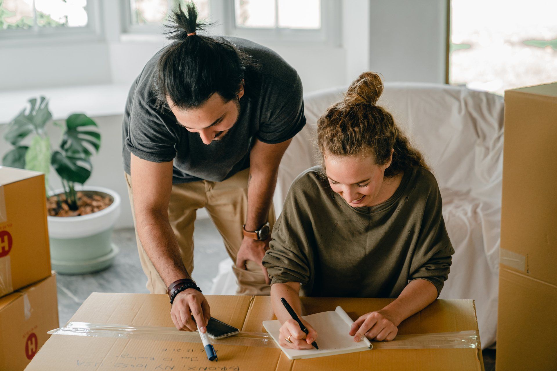 A man and a woman are sitting at a table with cardboard boxes.