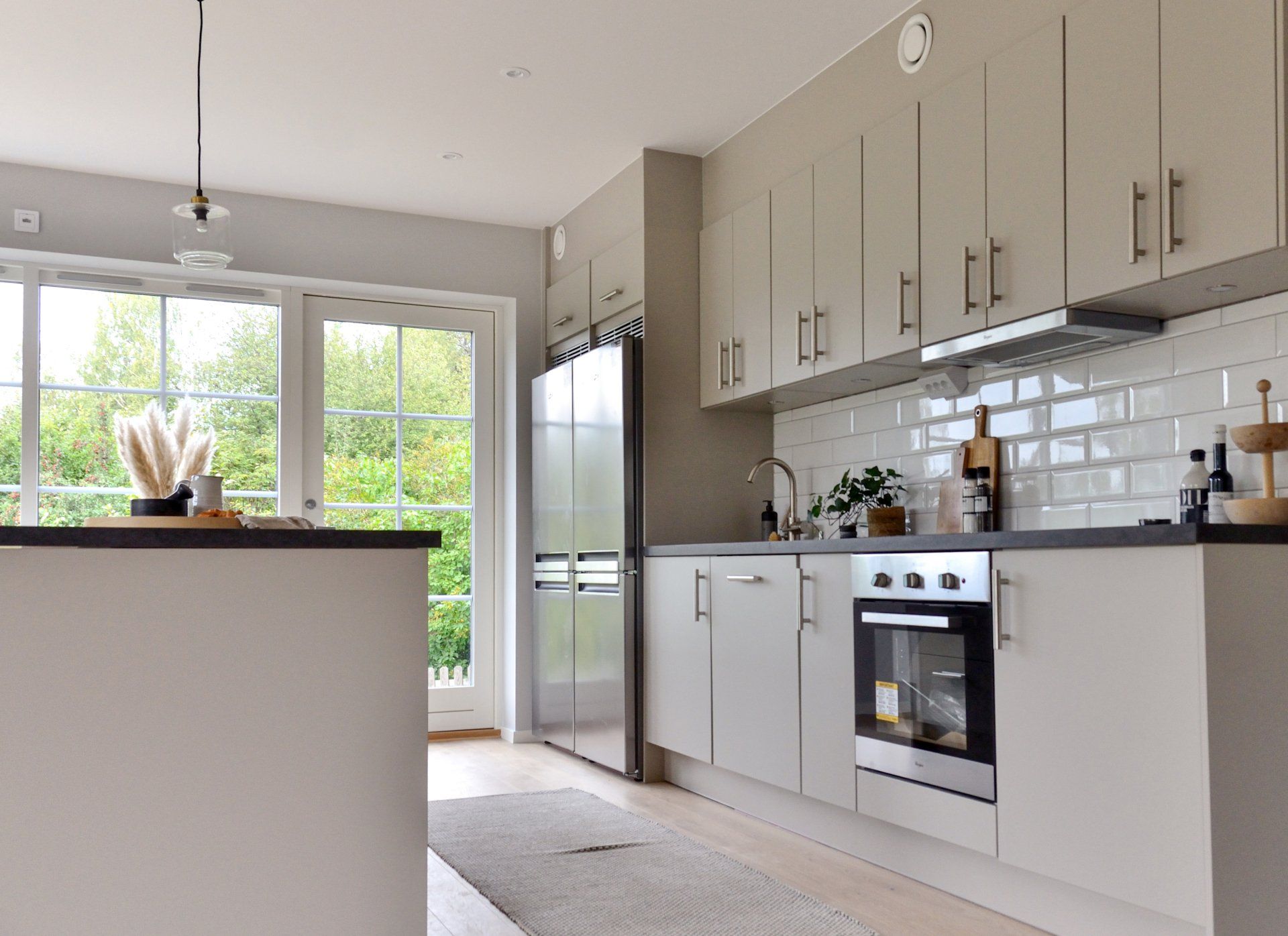Modern kitchen showcases all neutral cabinetry with a simple white tile backsplash.