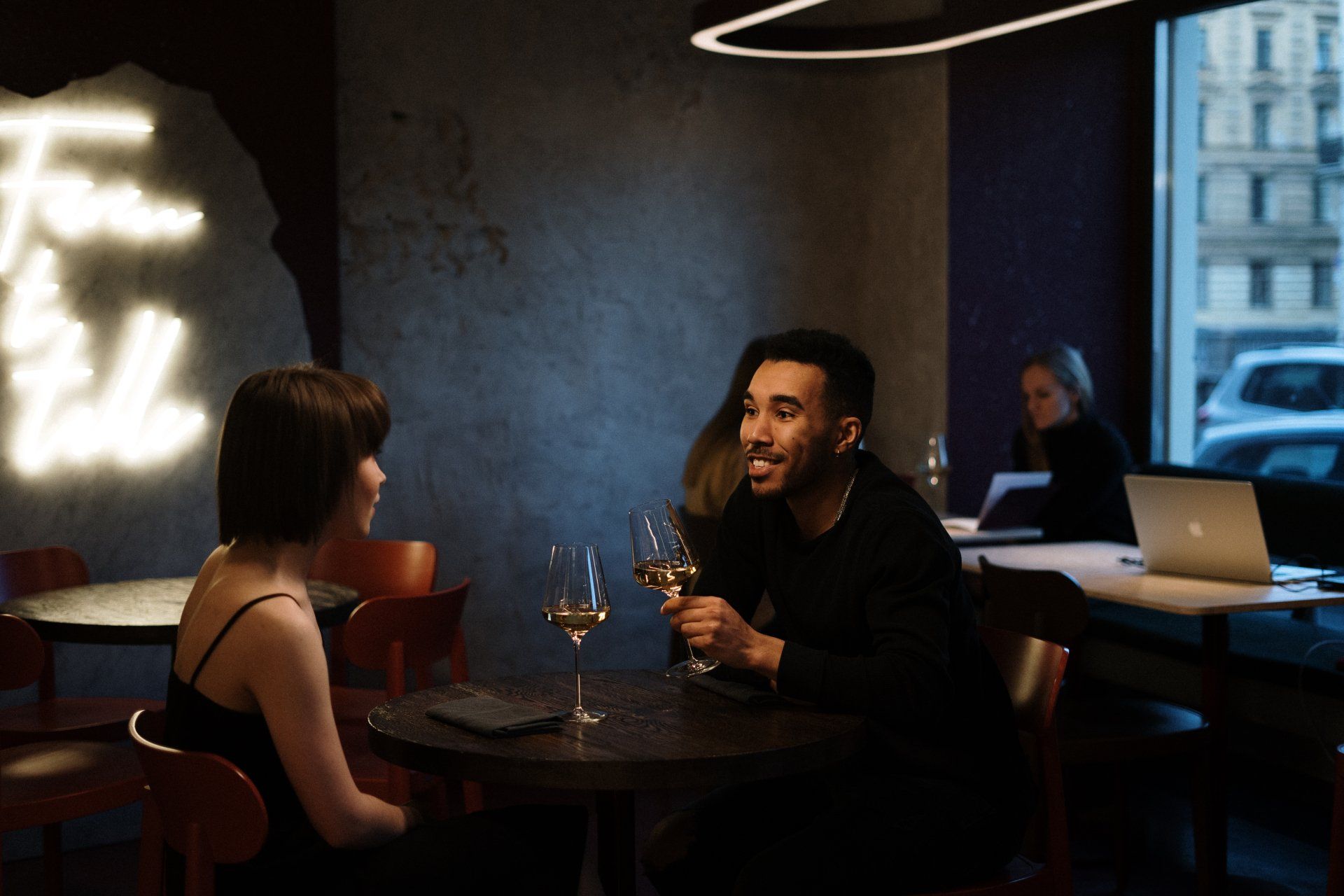 A man and a woman are sitting at a table drinking wine.