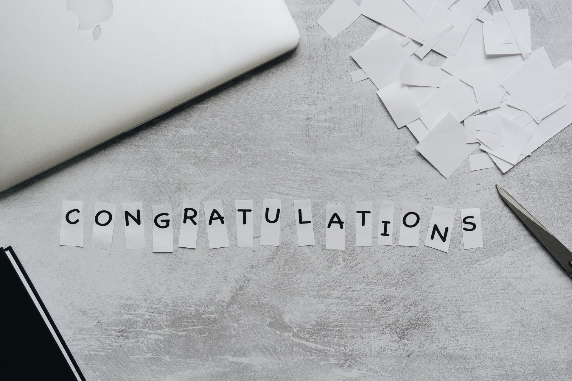 The word congratulations is written on a piece of paper on a table.