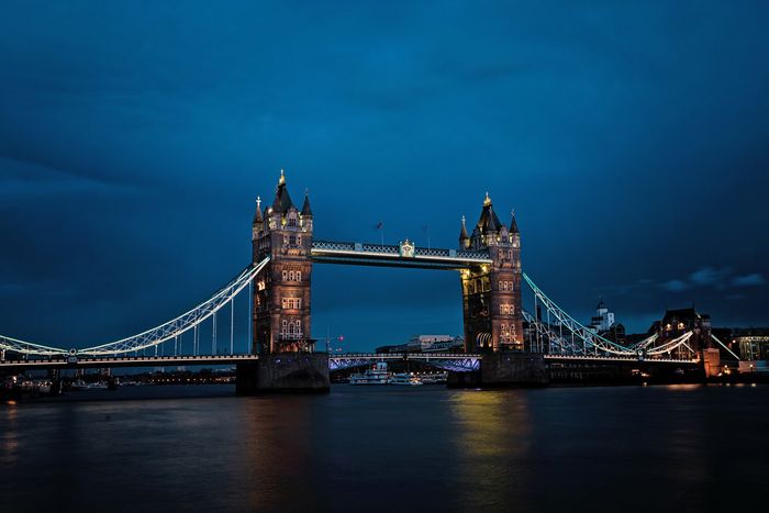The tower bridge in london is lit up at night.