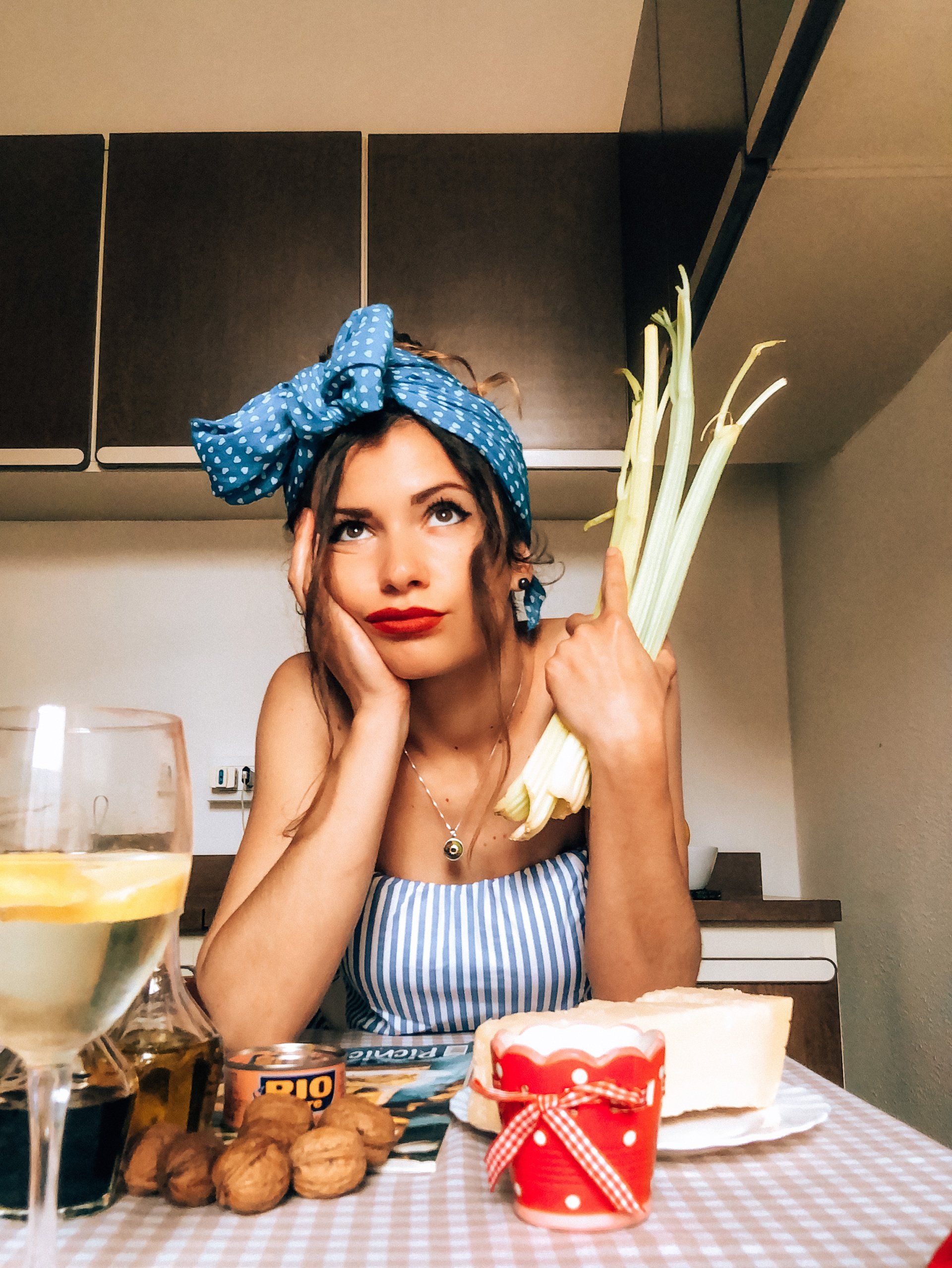 A woman is sitting at a table holding a bunch of celery