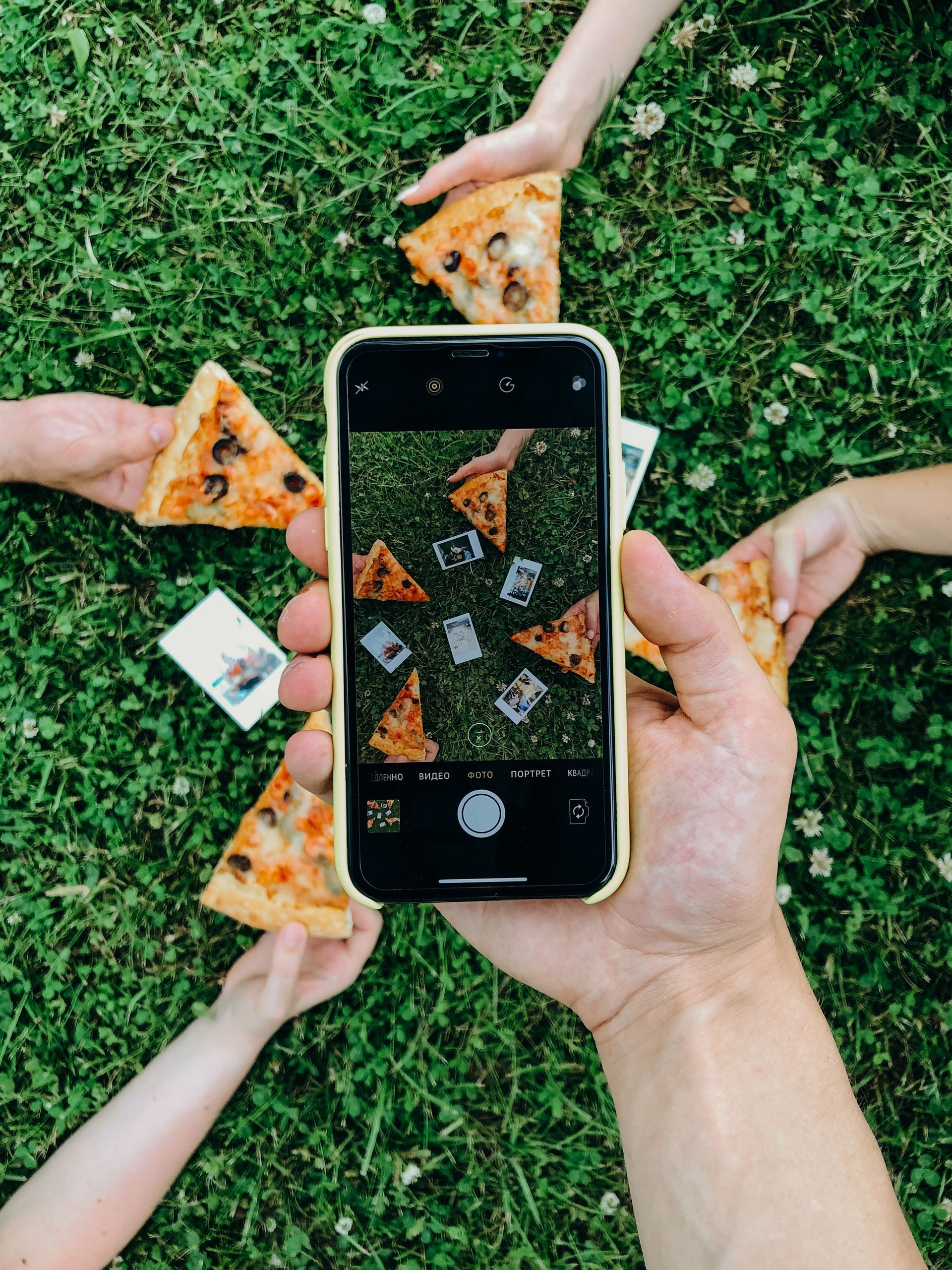A person is taking a picture of pizza slices with a cell phone.