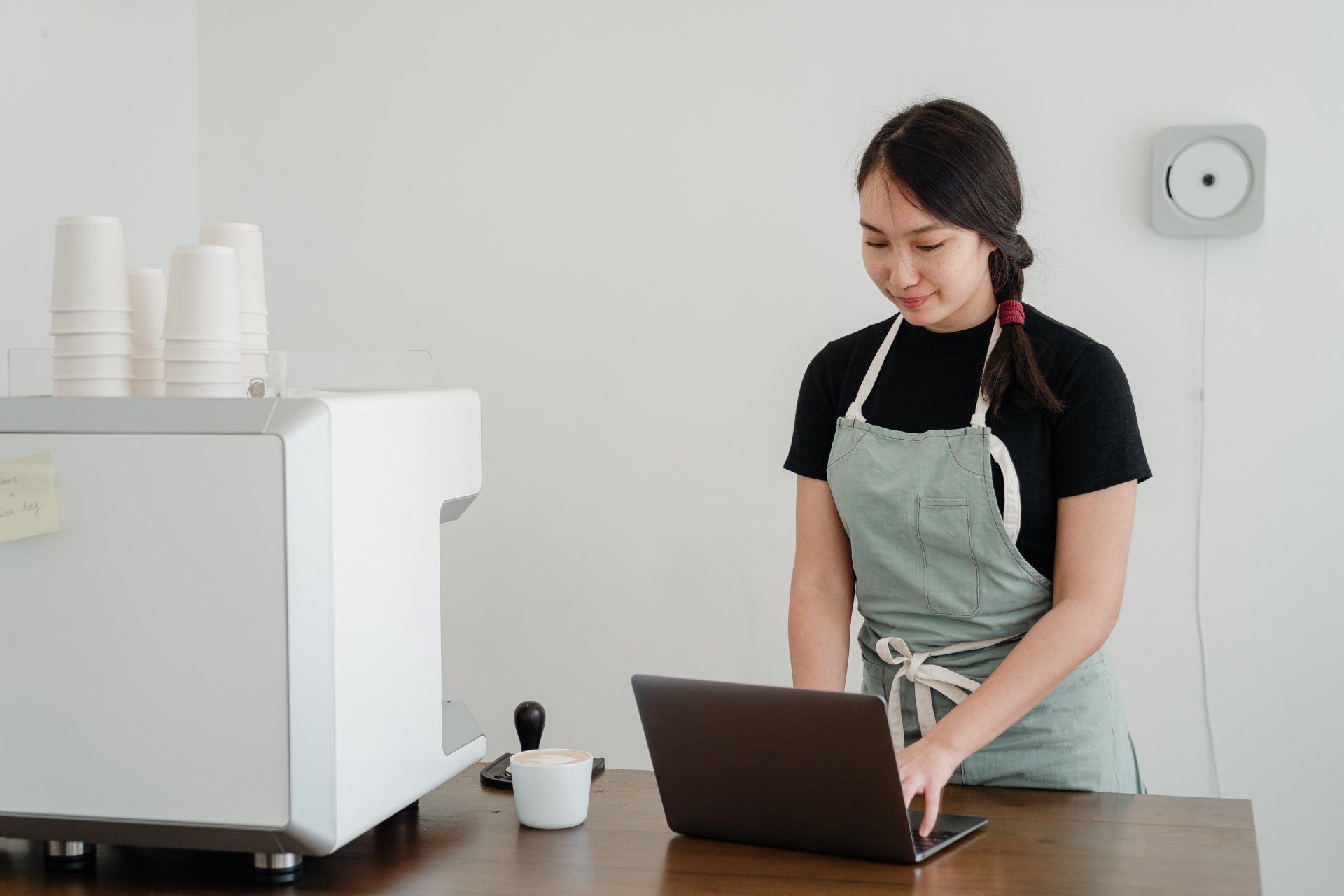 A woman in an apron is using a laptop computer.