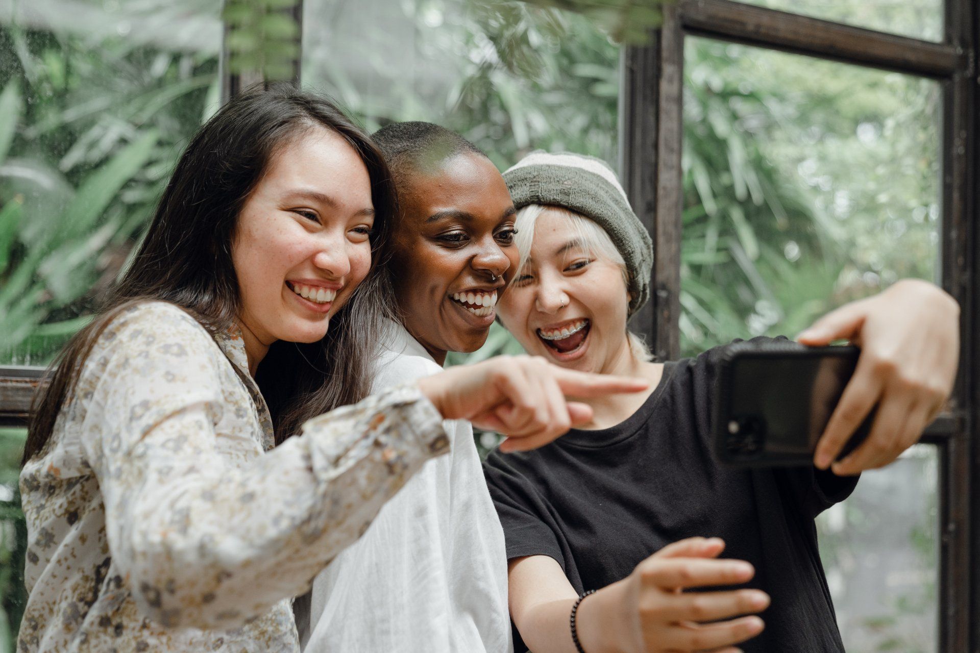 Three women are taking a selfie with a cell phone.