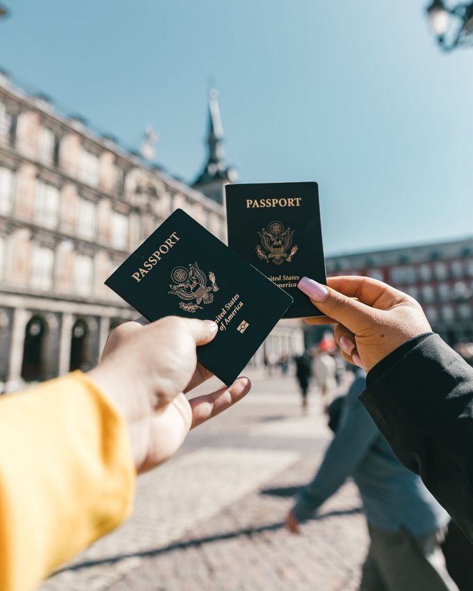 A person holding two passports in front of a building