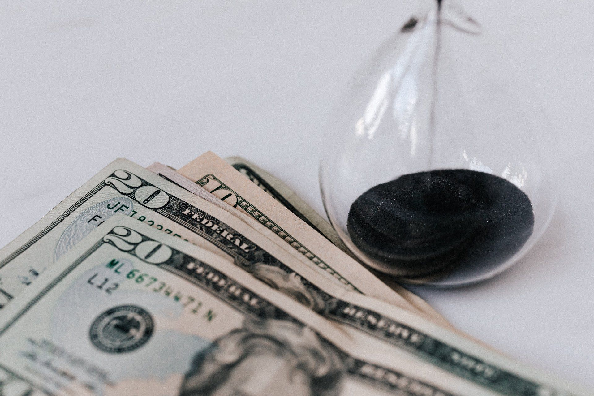 A hourglass is sitting on top of a pile of money.