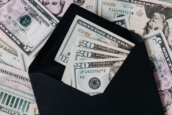 a black envelope filled with money is sitting on top of a pile of money .