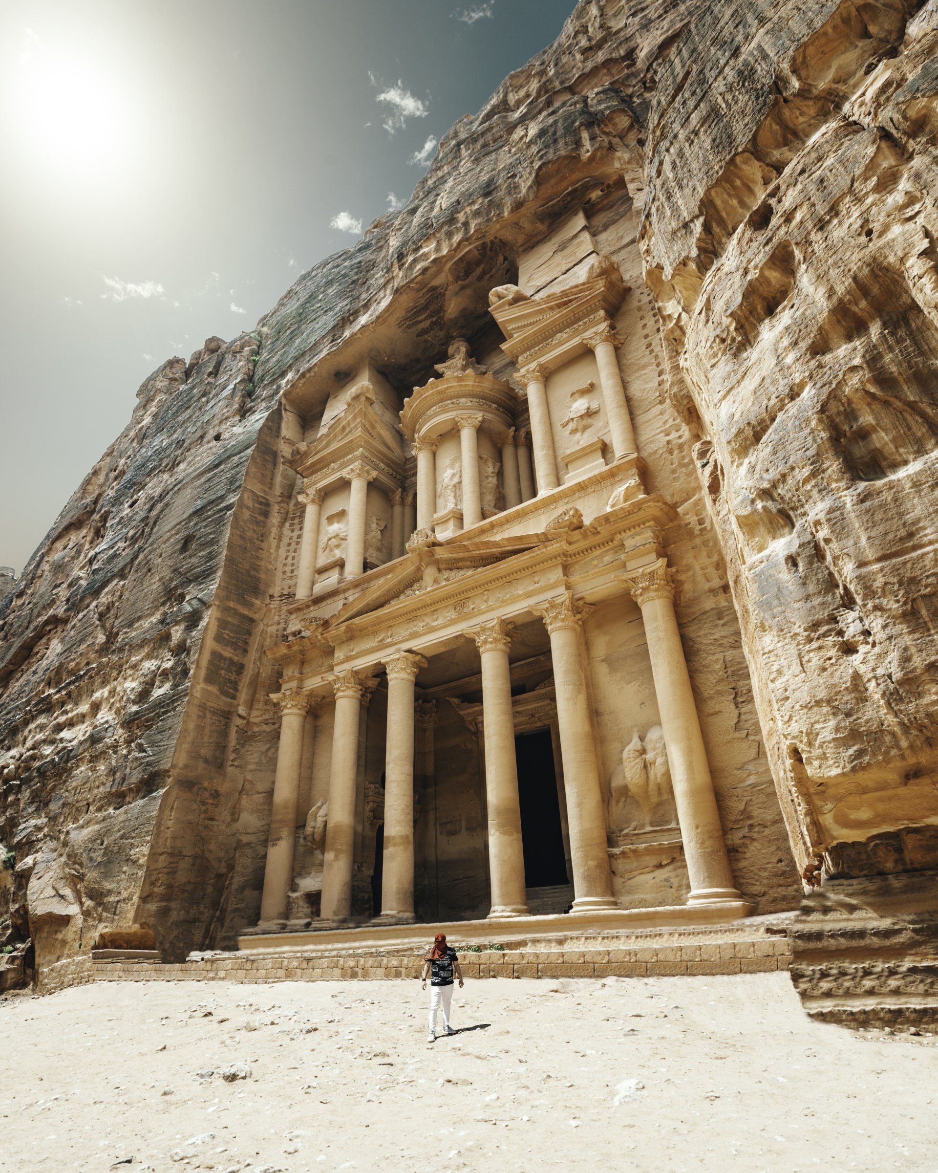 A man is standing in front of a large stone building.