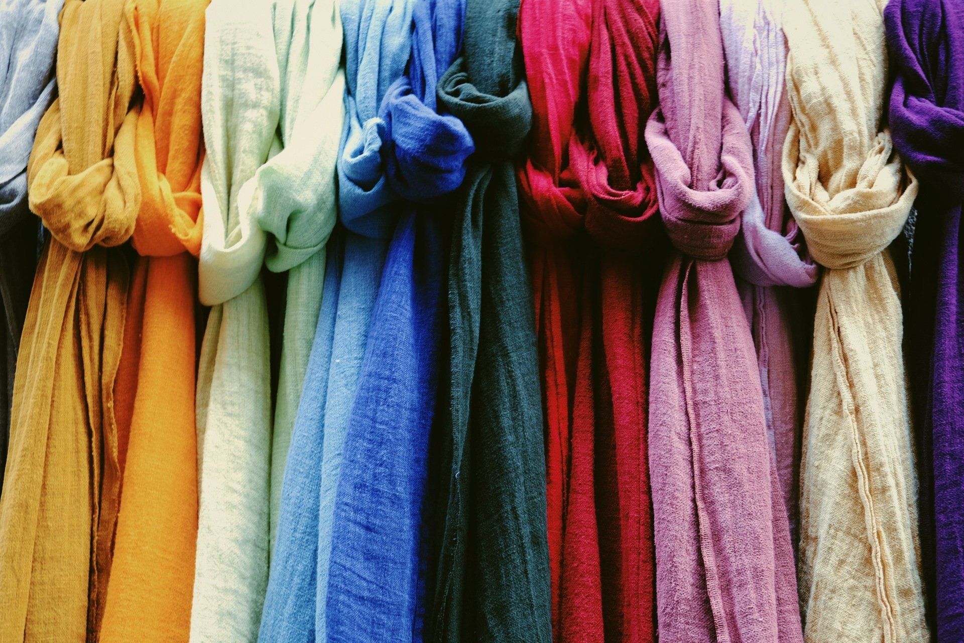 A row of colorful scarves hanging on a shelf.
