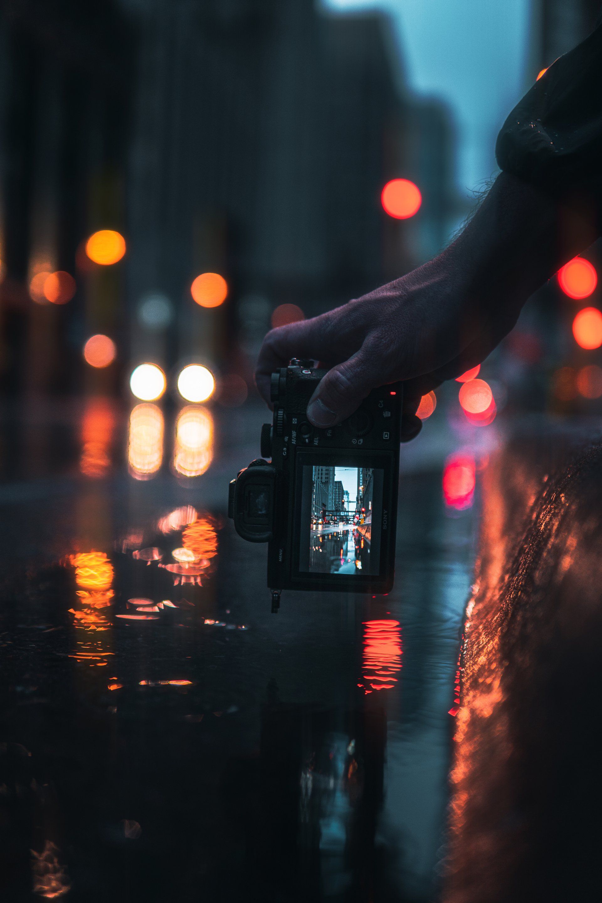 Une personne prend une photo avec un appareil photo sous la pluie.