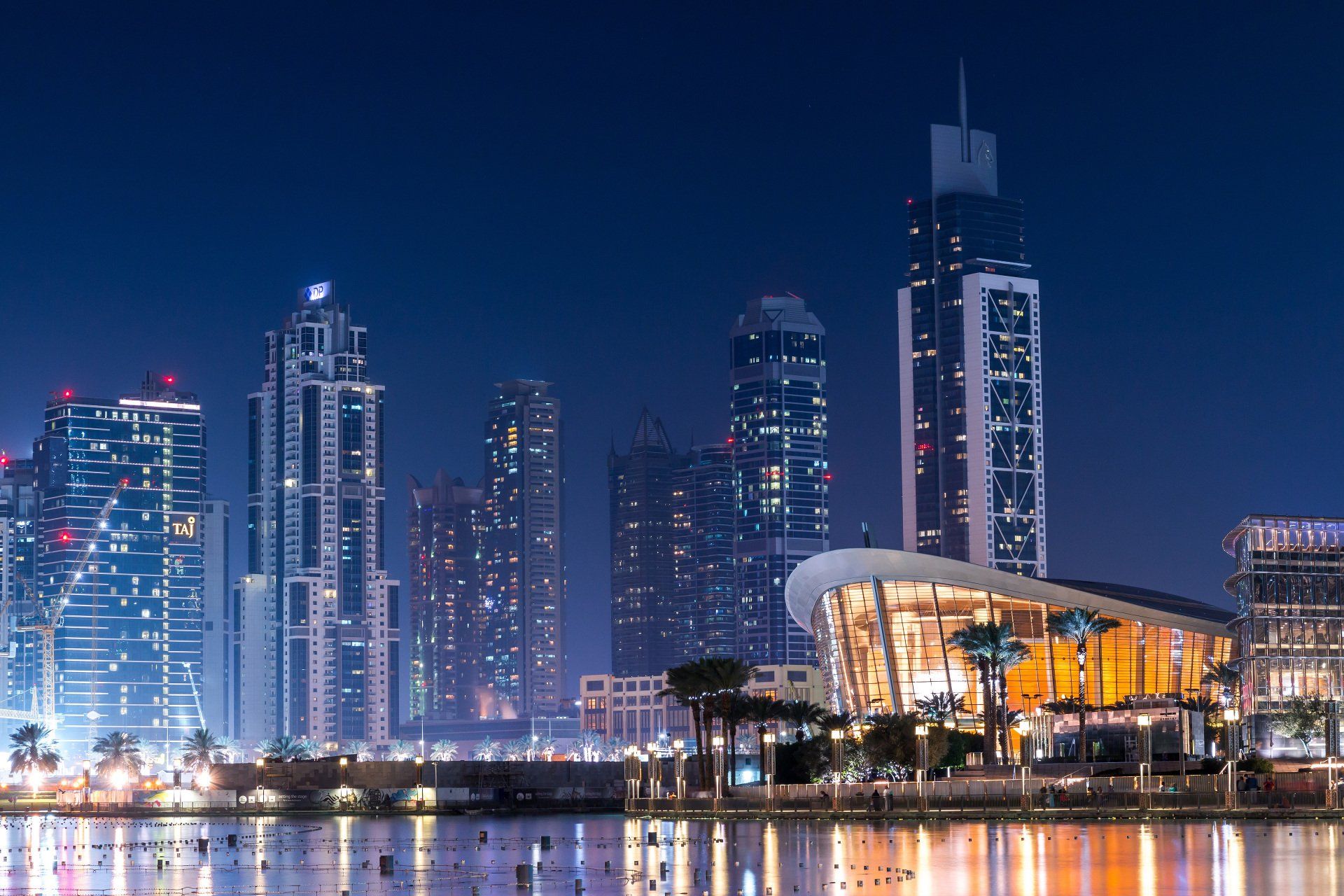 A city skyline at night with a large body of water in the foreground.