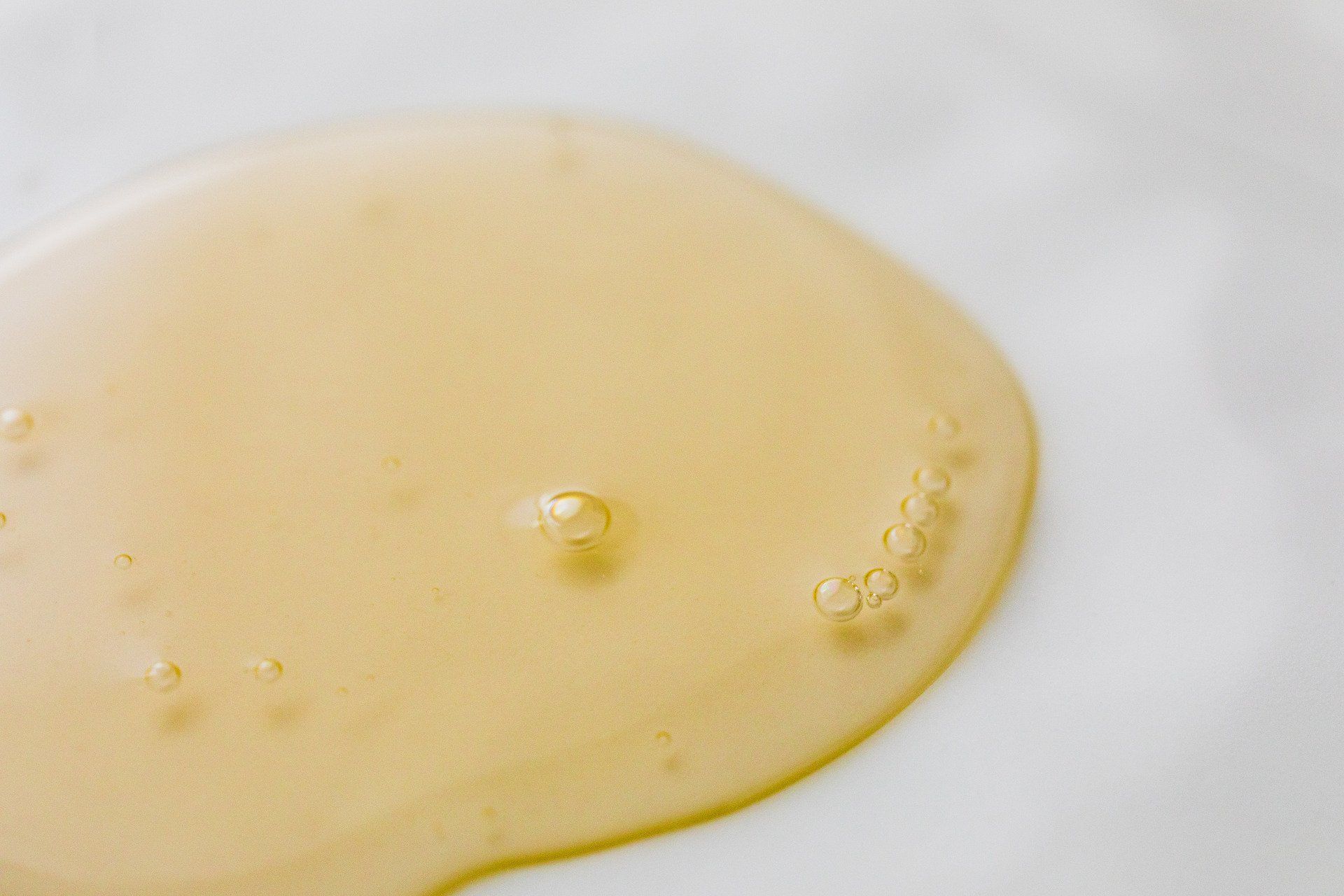 A close up of a yellow liquid on a white surface.