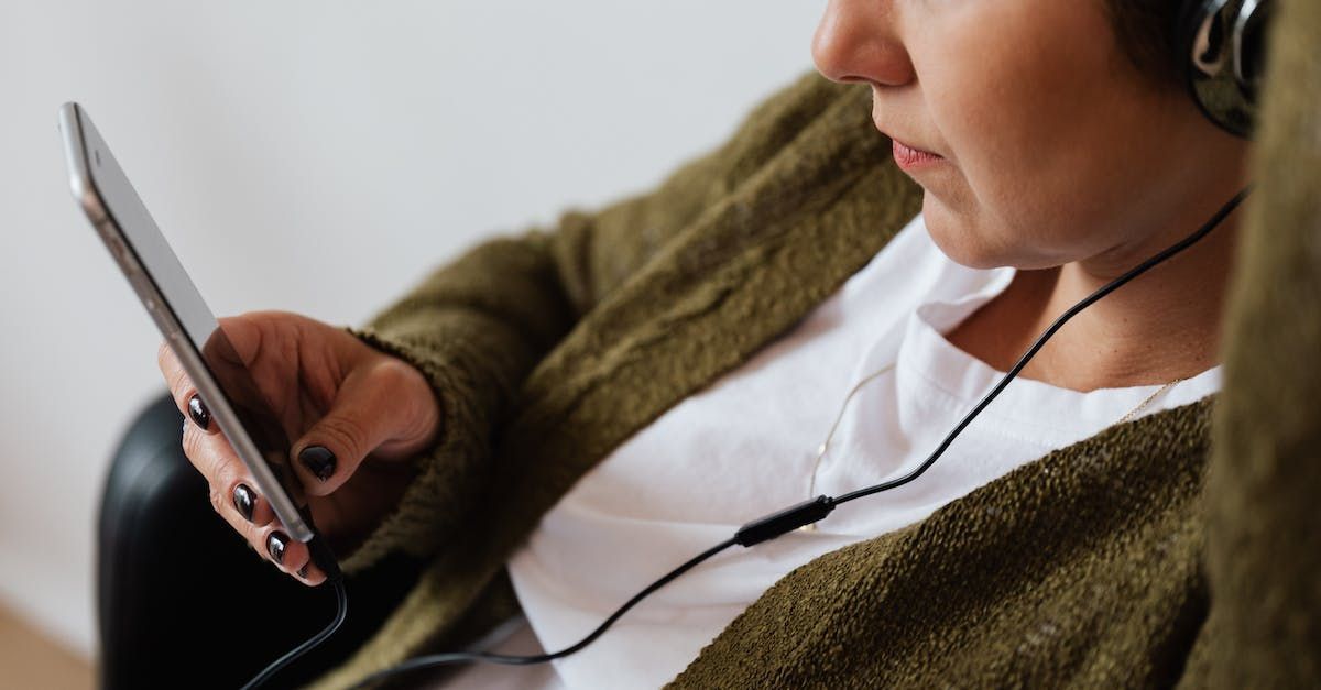 A woman wearing headphones is using a tablet computer.