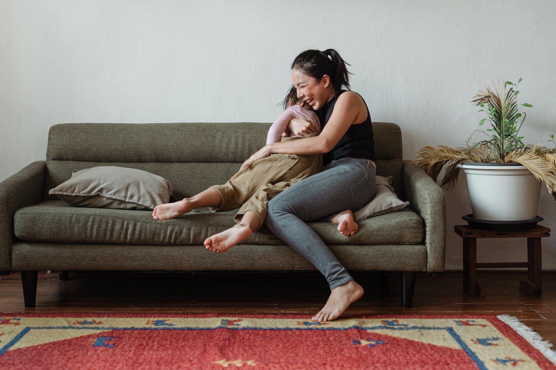 Una mujer está sentada en un sofá sosteniendo a un niño.