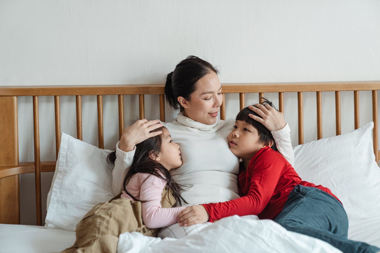 Children snuggling in bed with their mother