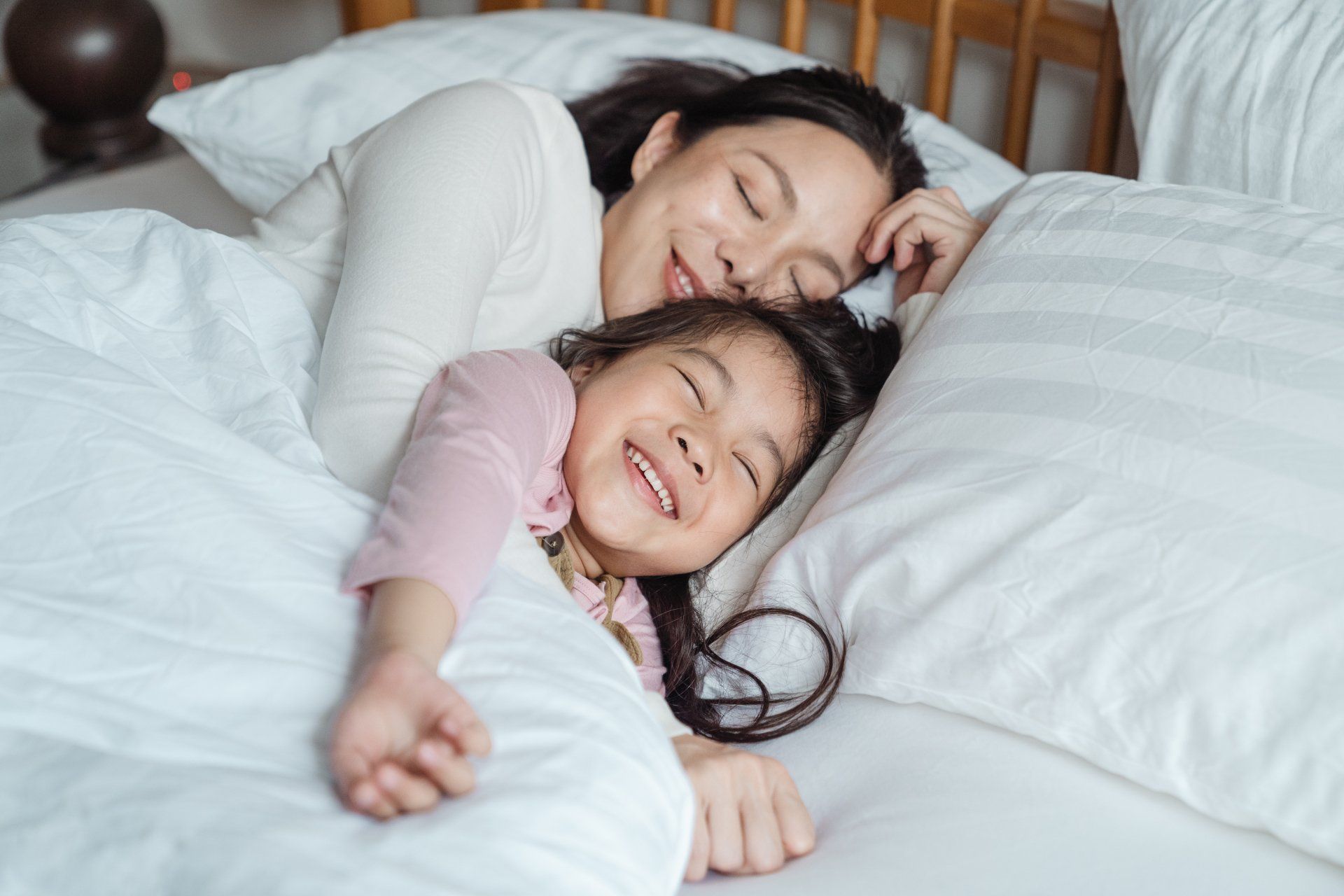 A woman and a little girl are sleeping on a bed.