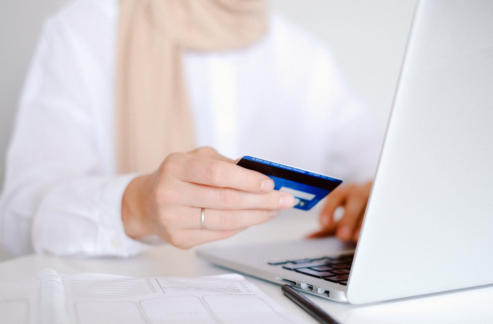 a woman is holding a credit card while using a laptop computer .