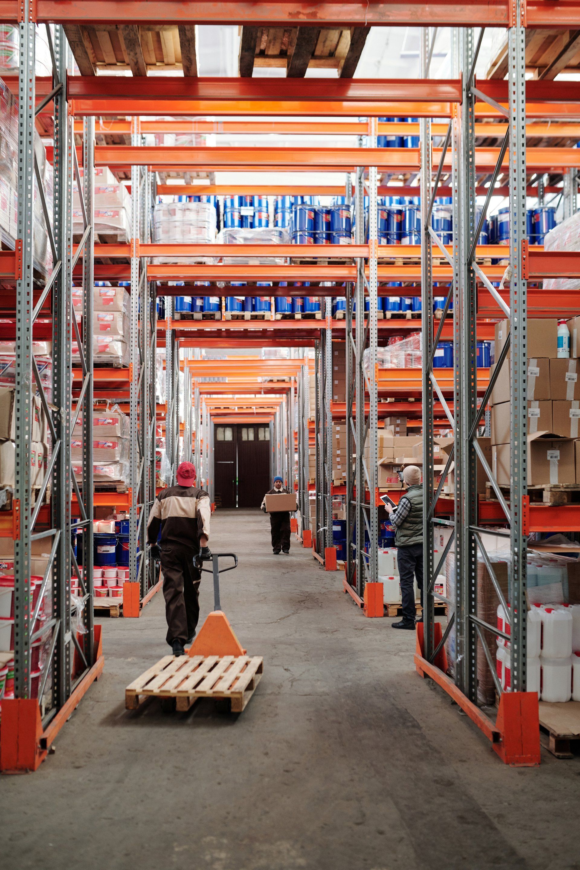A man is pushing a pallet in a warehouse.