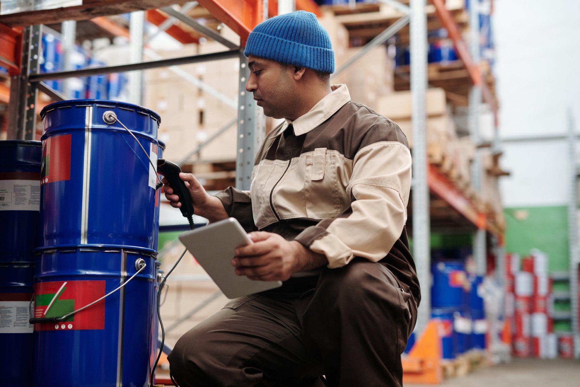 a man is sitting in a warehouse using a tablet and a scanner .