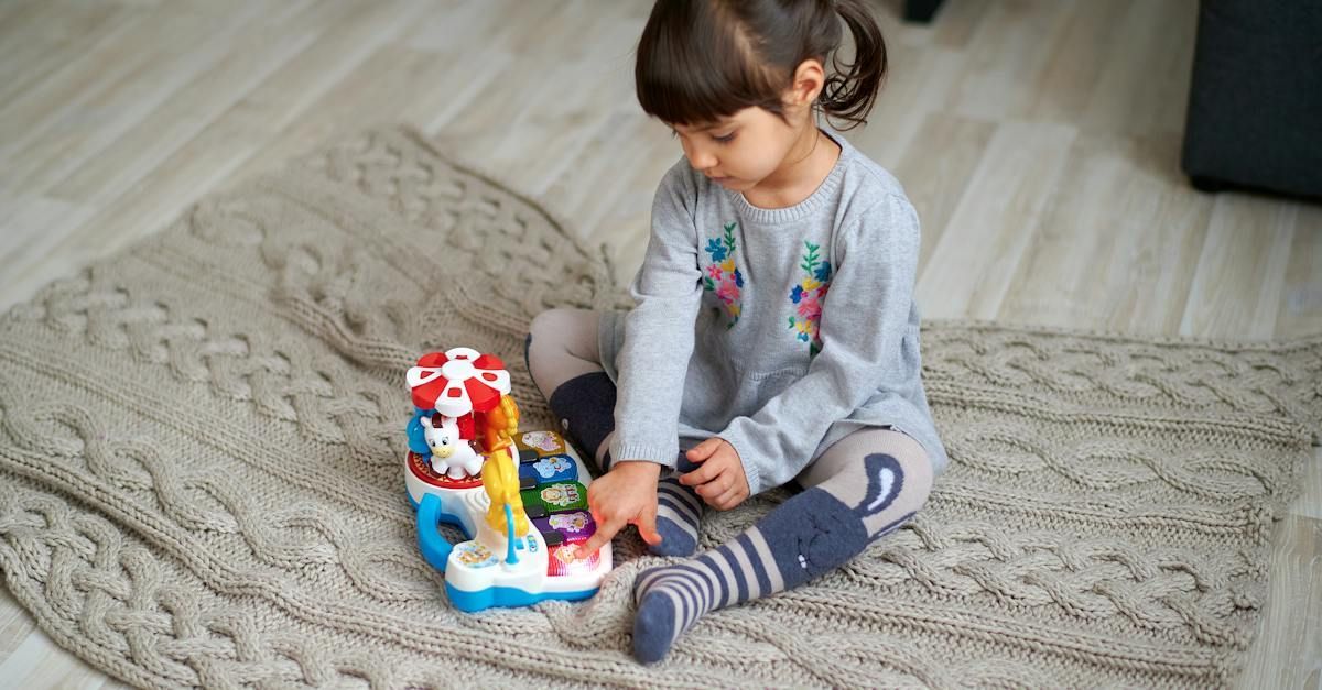 A little girl is sitting on the floor playing with a toy.
