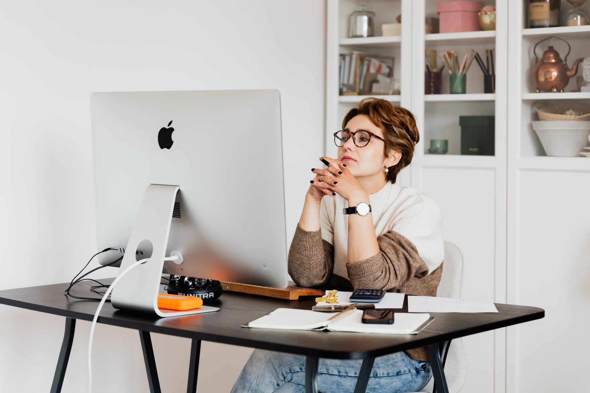 A woman is sitting at a desk in front of a computer.