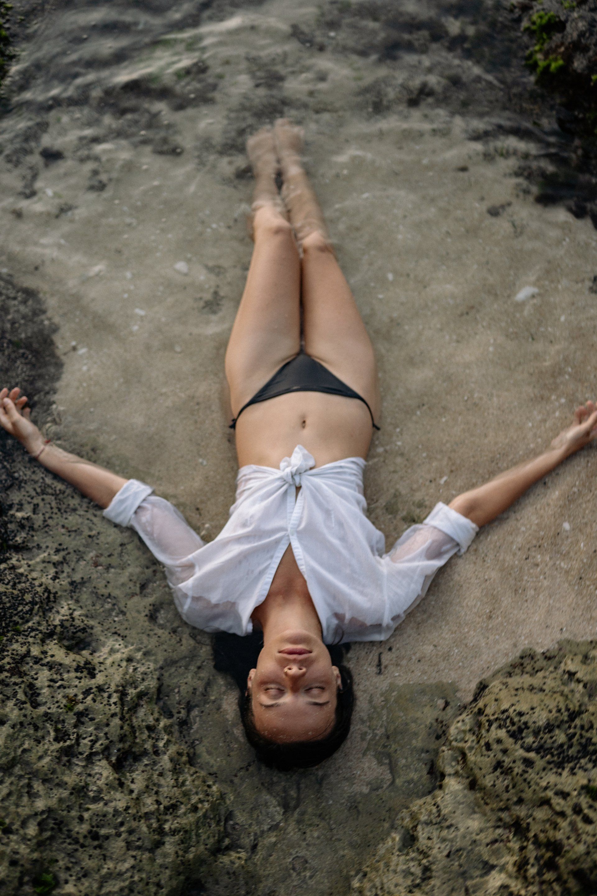 A woman in a bikini is laying on her back in the water.