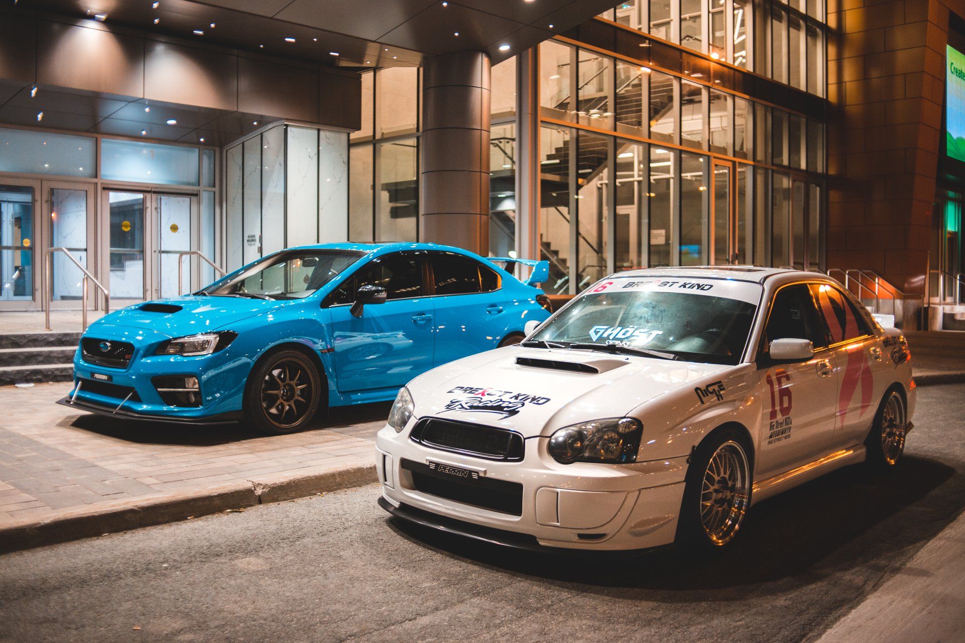 two cars are parked on the side of the road in front of a building .