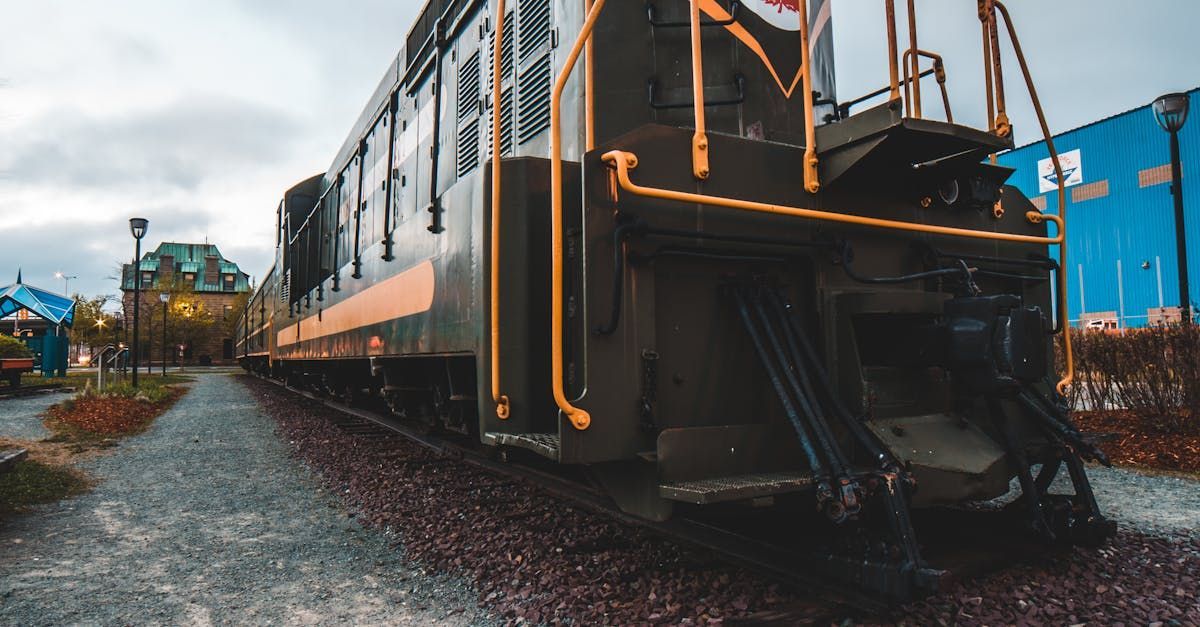 A train is parked on the tracks in front of a building.