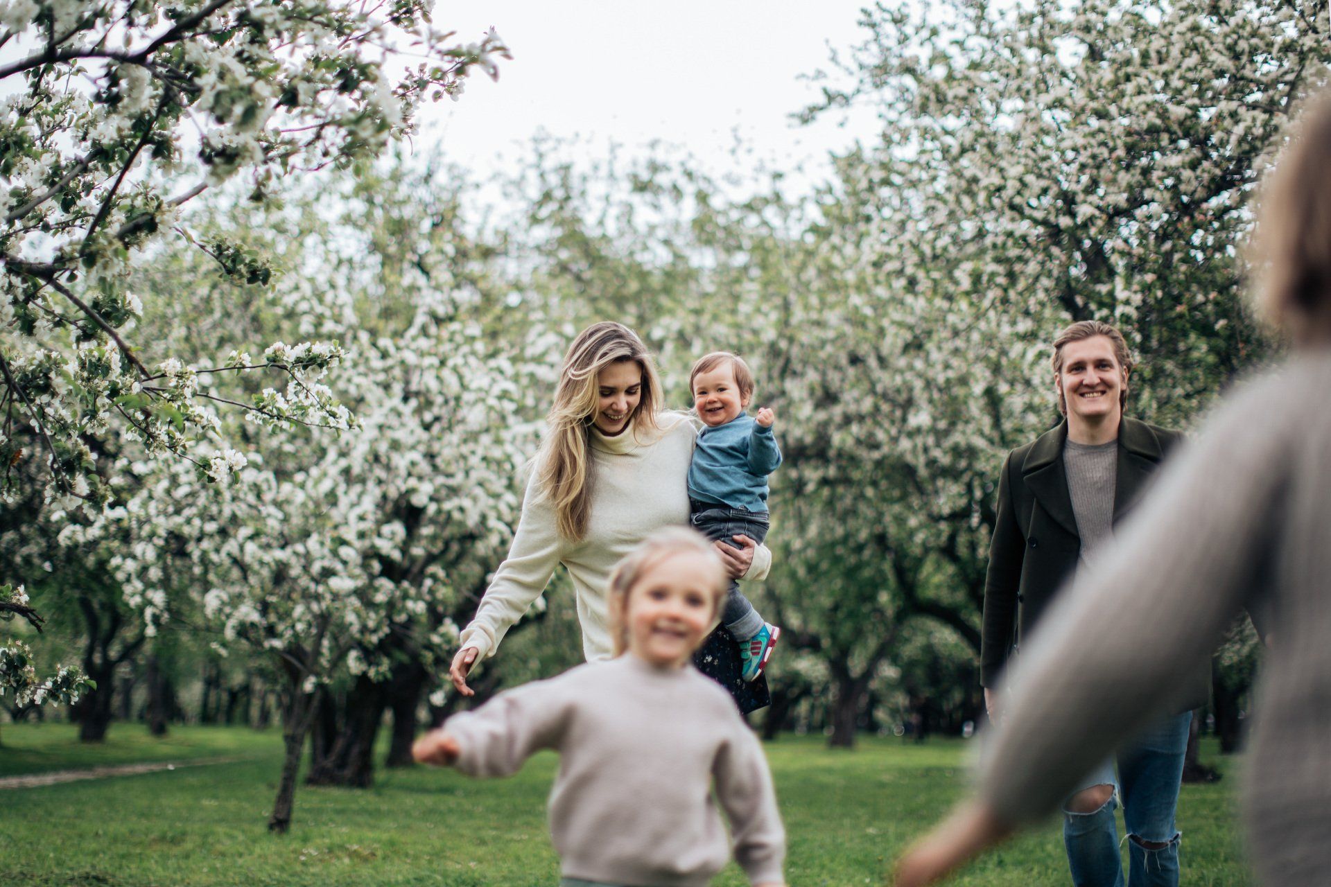 A family is walking through a park holding hands.