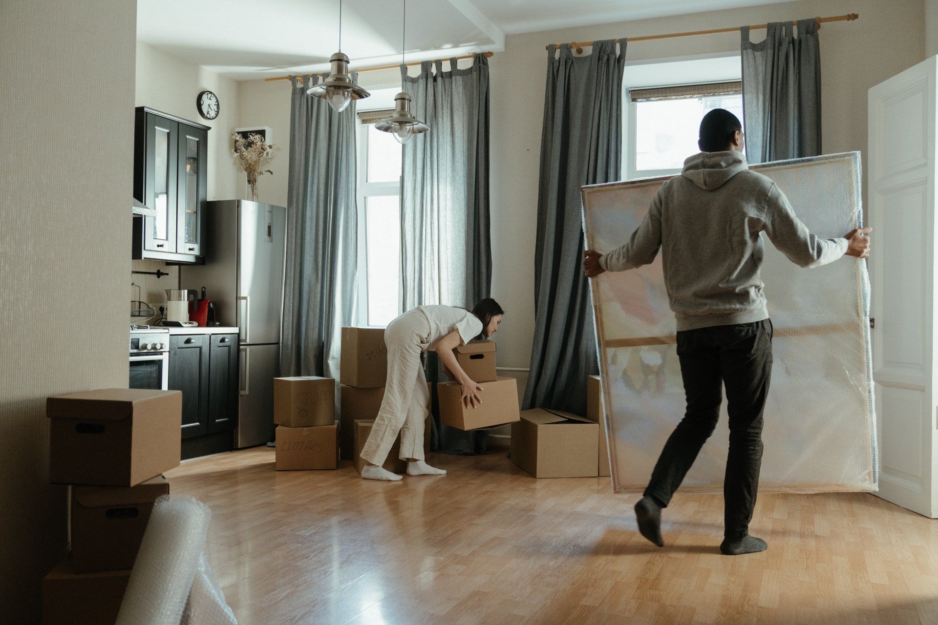A man is carrying a large piece of paper in a living room.