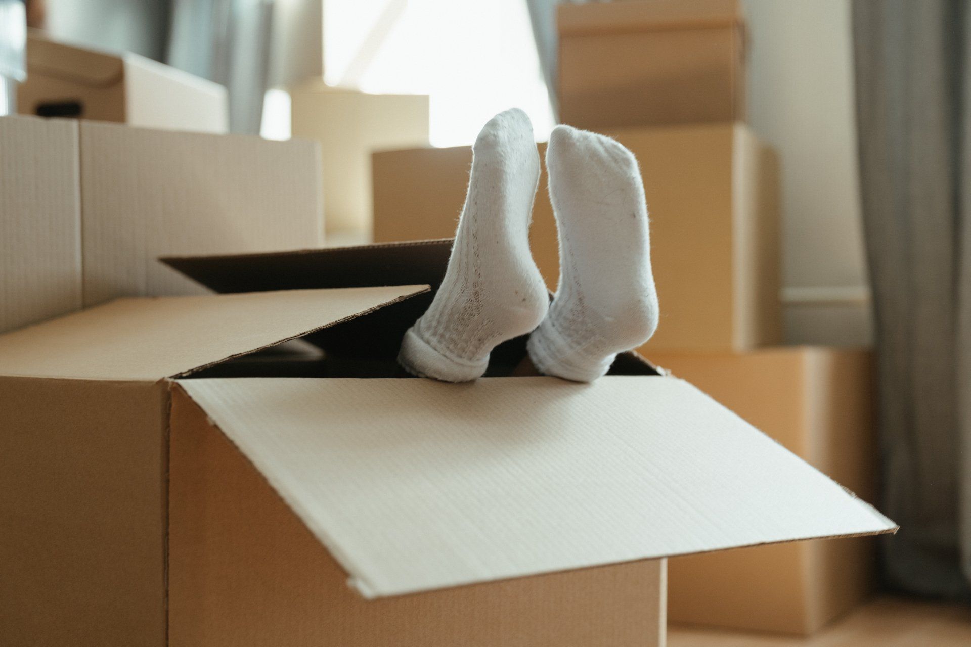 A person 's feet sticking out of a cardboard box.