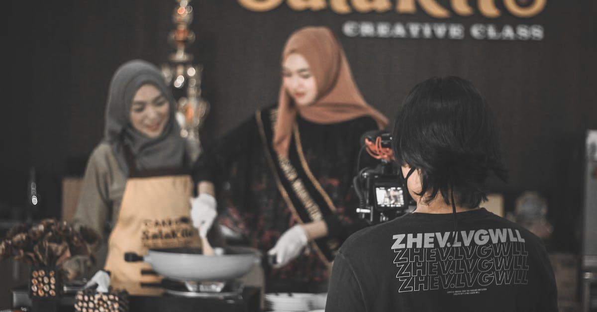 A man is taking a picture of two women cooking in a kitchen.