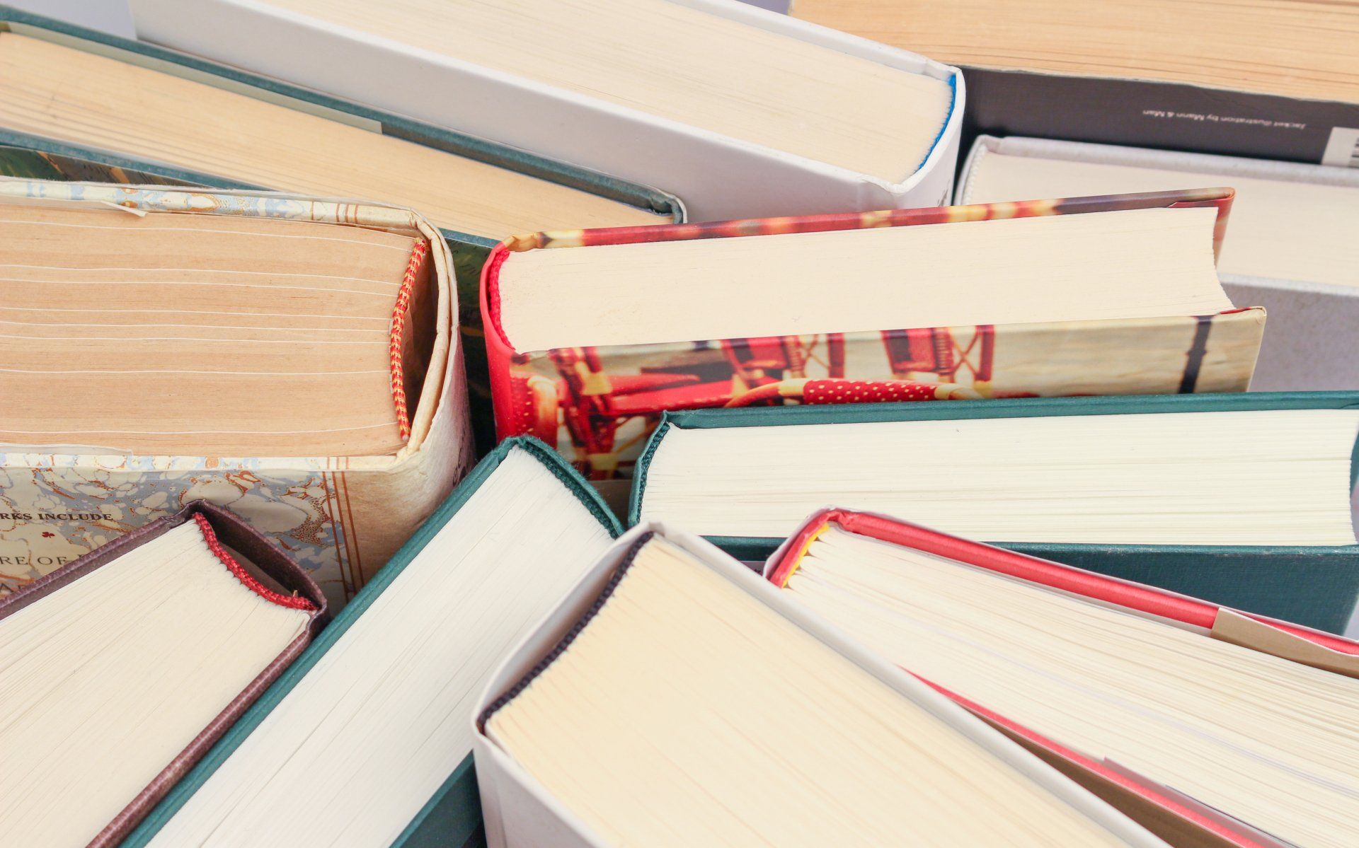 Stacked open books with cream pages and red-edged covers in a close-up view