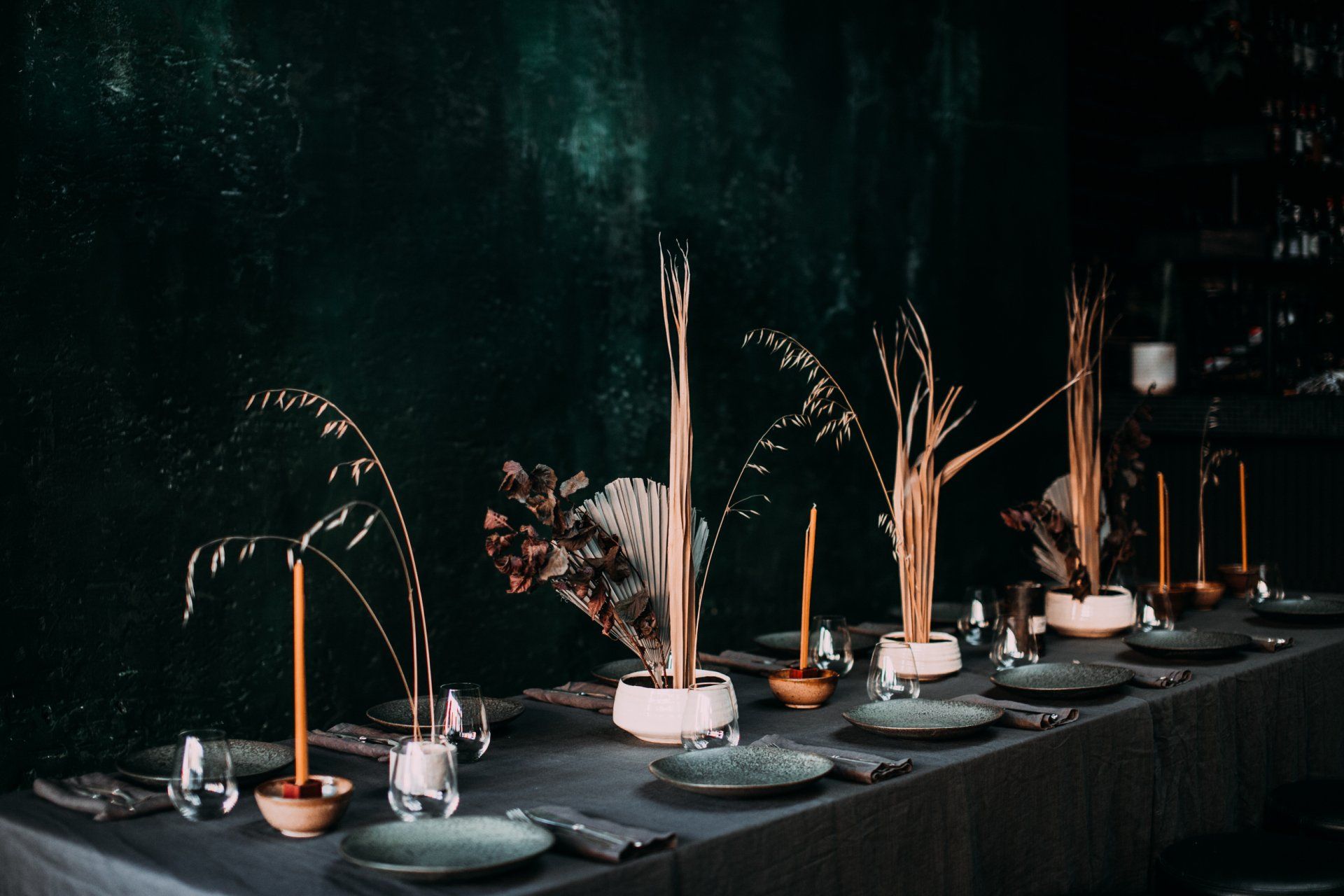 A long table with plates , candles , vases and flowers on it.