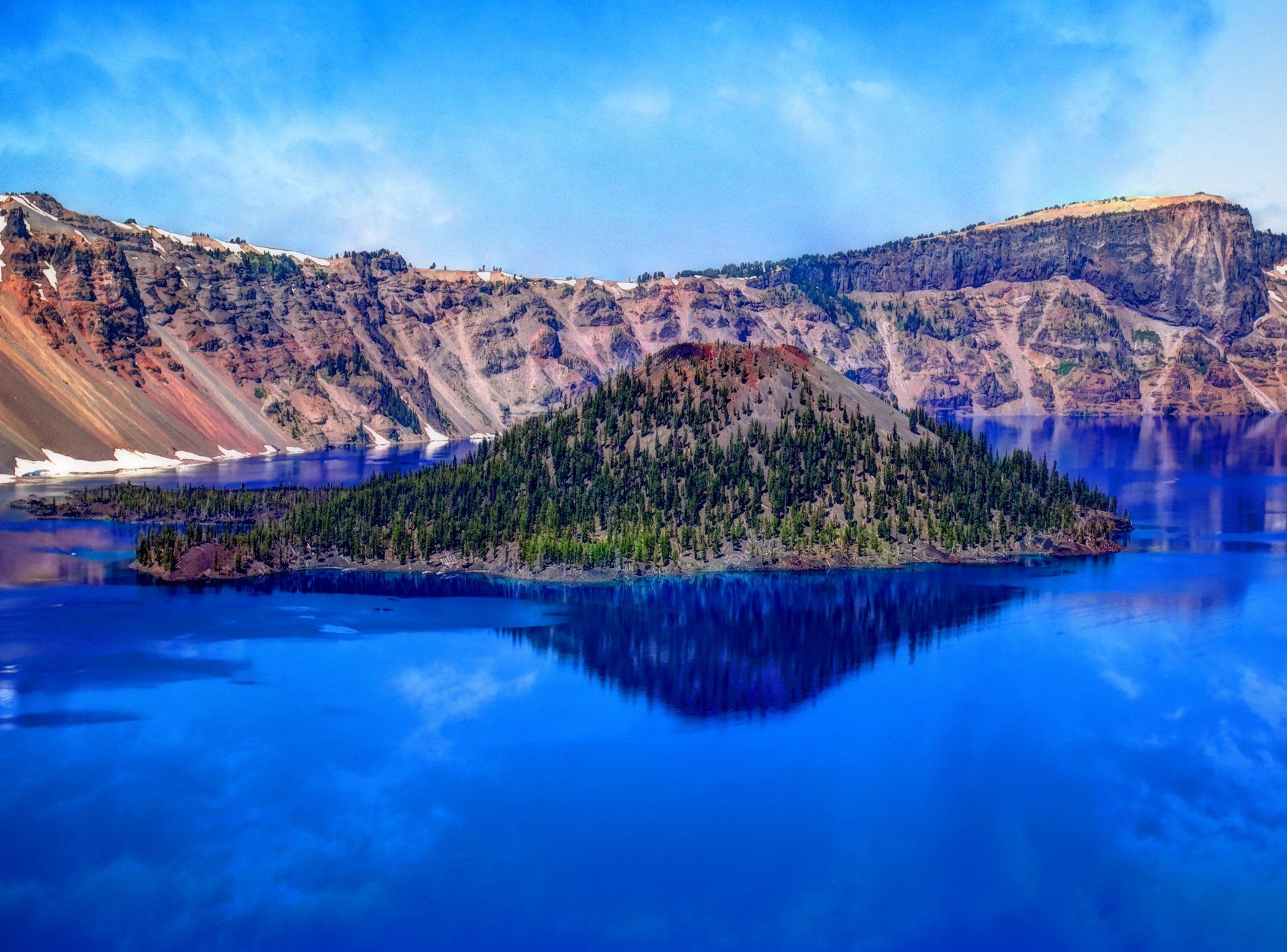 A small island in the middle of a lake with mountains in the background.