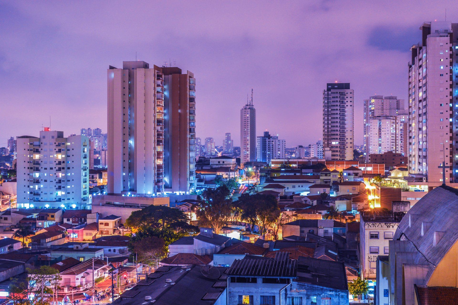 An aerial view of a city at night with a purple sky