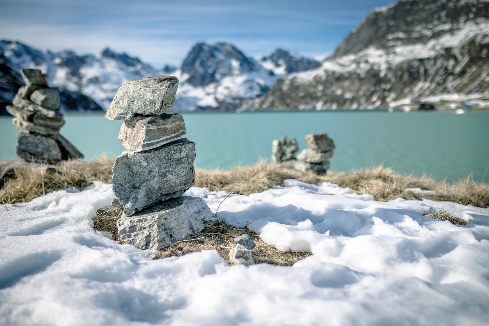 Ein Steinhaufen liegt im Schnee neben einem See.