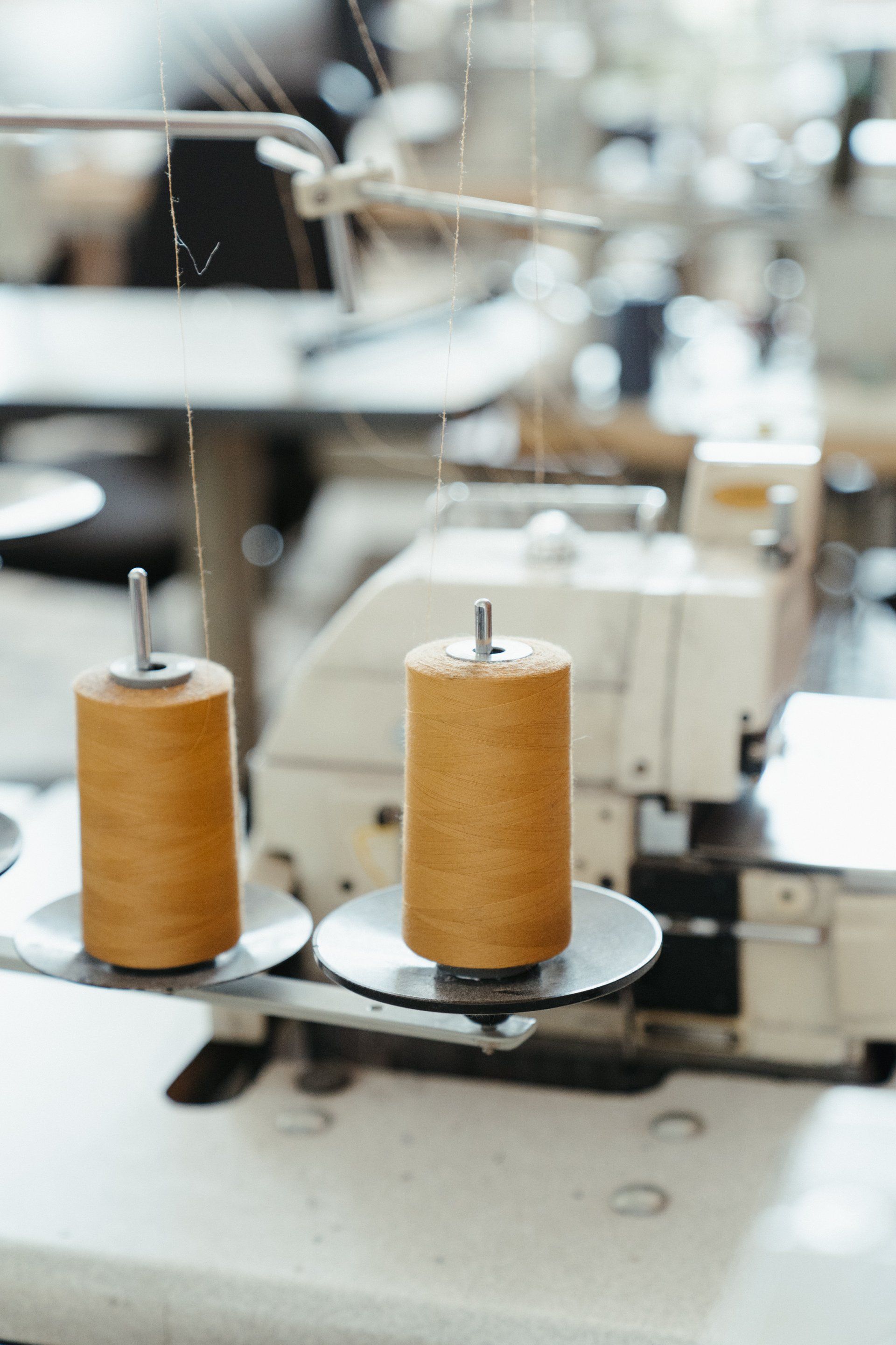 Twee klossen oranje garen op een naaimachine.