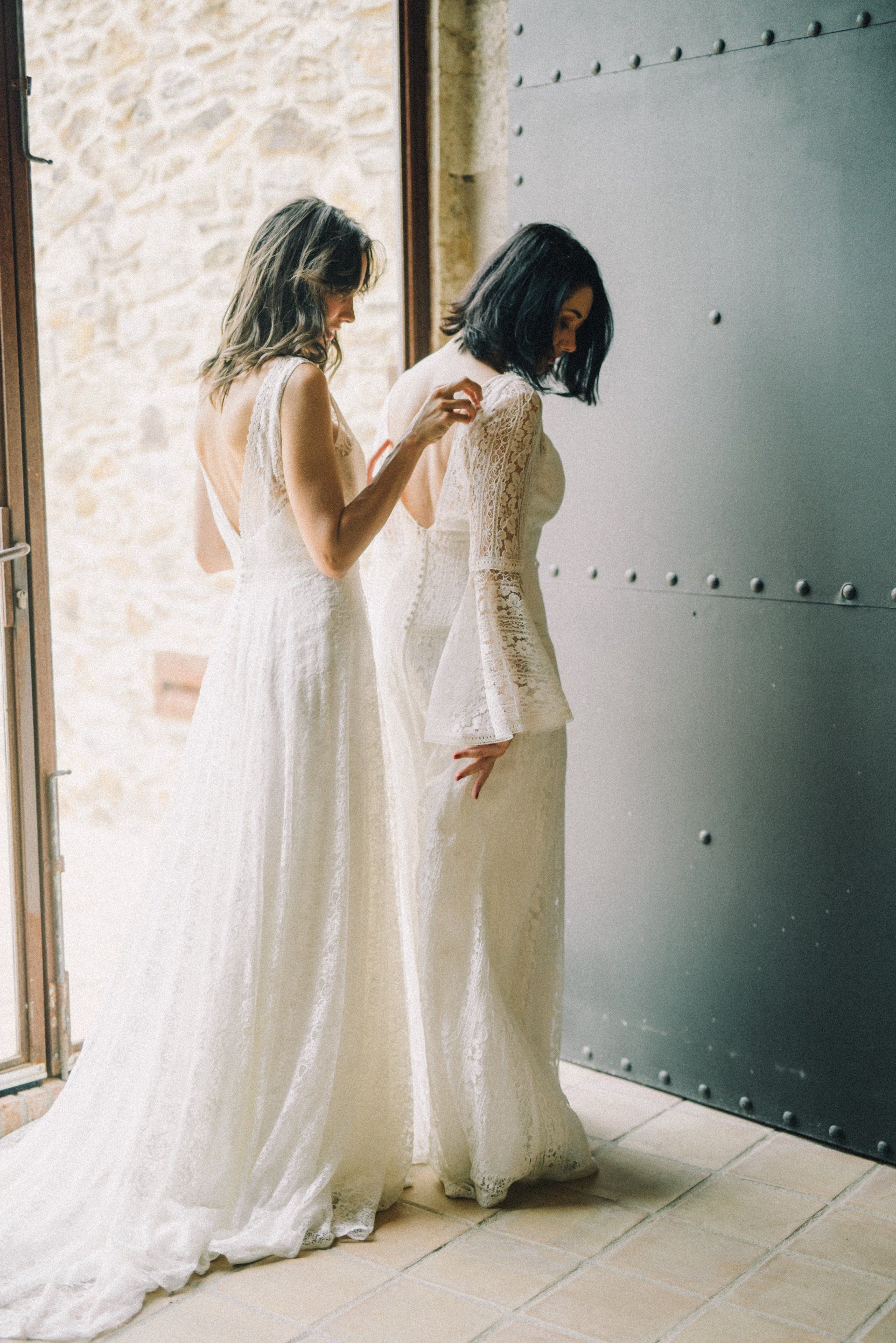 Two women in white dresses are standing next to each other in a room.