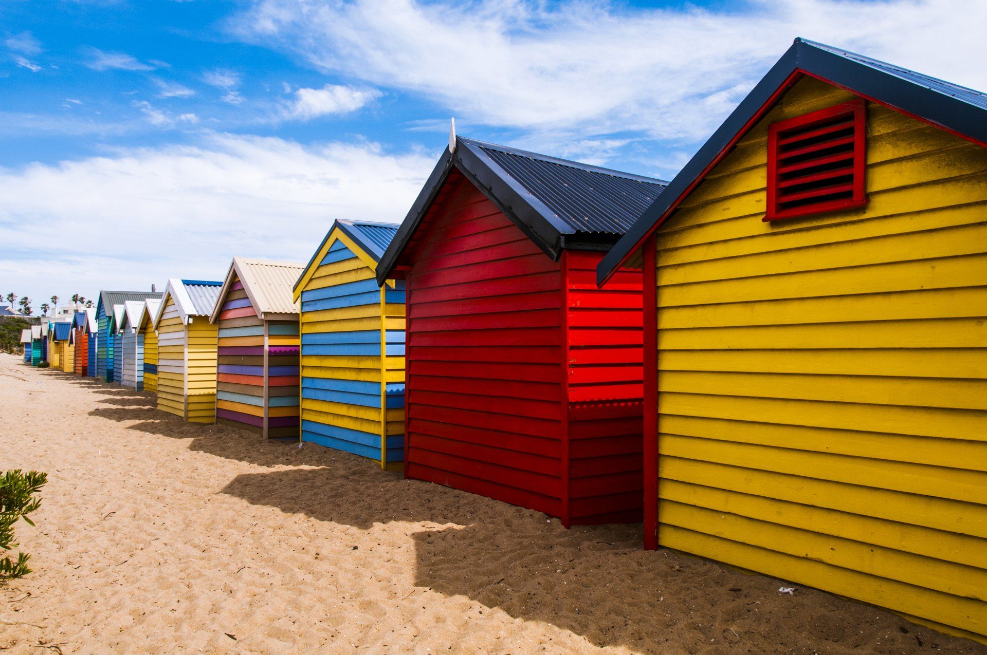 Uma fileira de cabanas de praia coloridas em uma praia arenosa.
