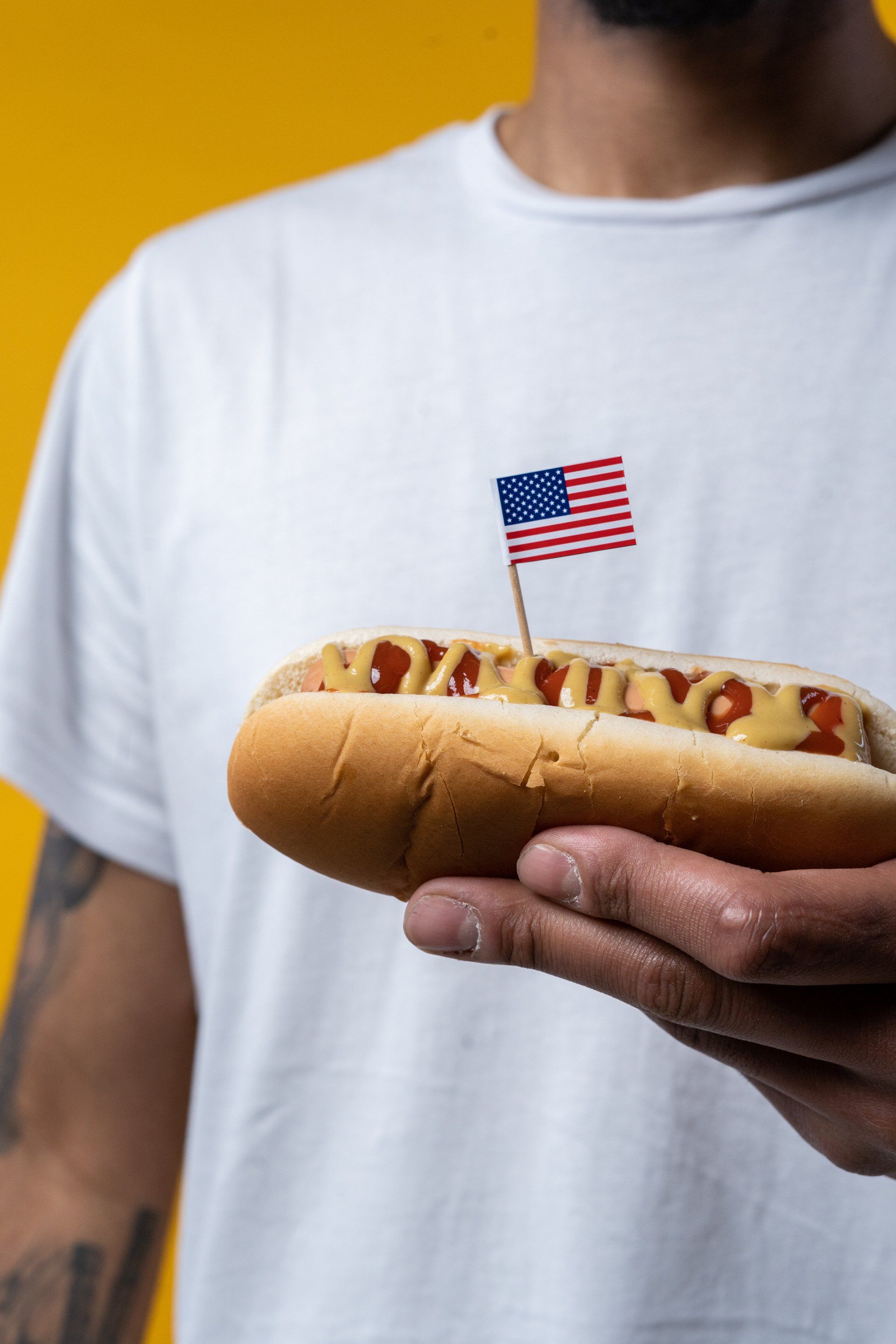 A man is holding a hot dog with an american flag sticking out of it.