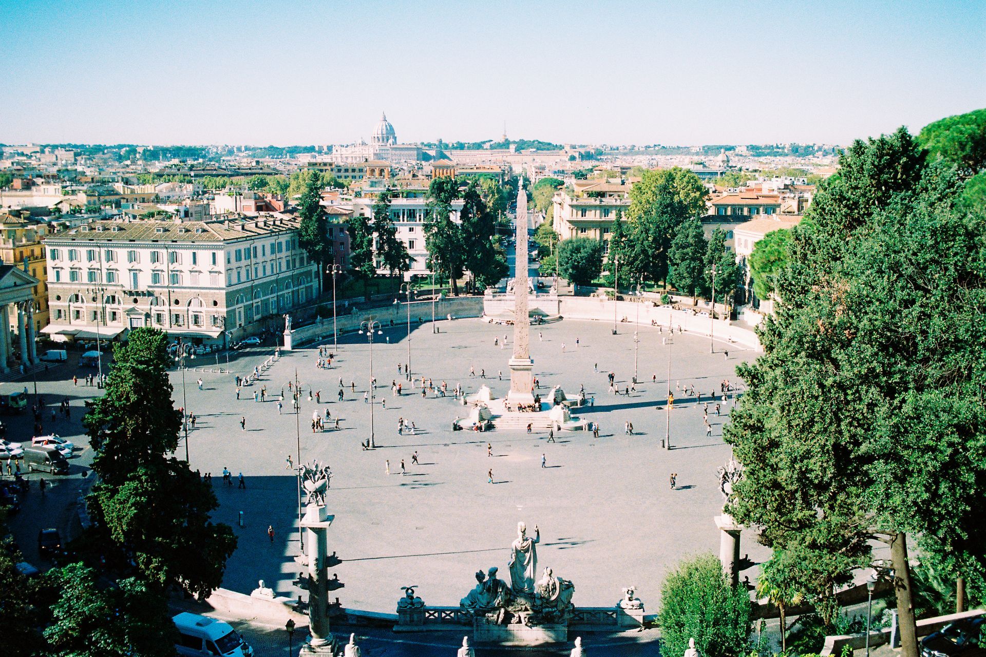 Ampia veduta aerea di Piazza del Popolo a Roma con un obelisco, edifici e persone.