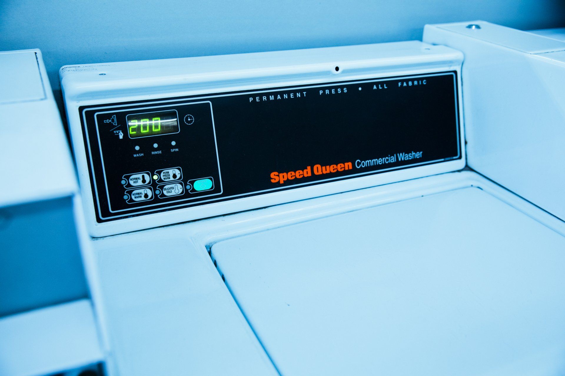 A white Speed Queen commercial washing machine. Control panel with buttons and display.