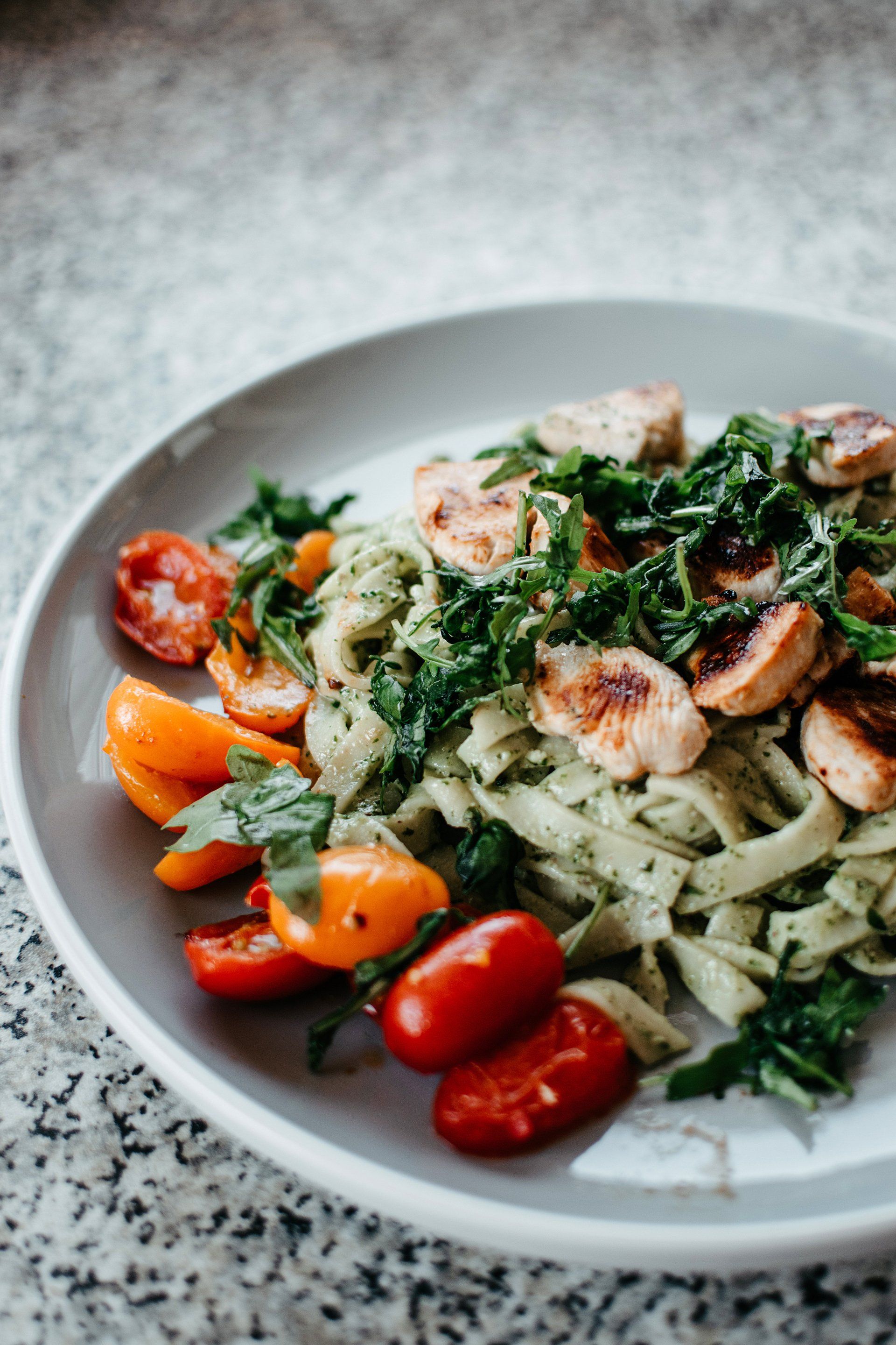 A plate of pasta with tomatoes and sausage on a table.