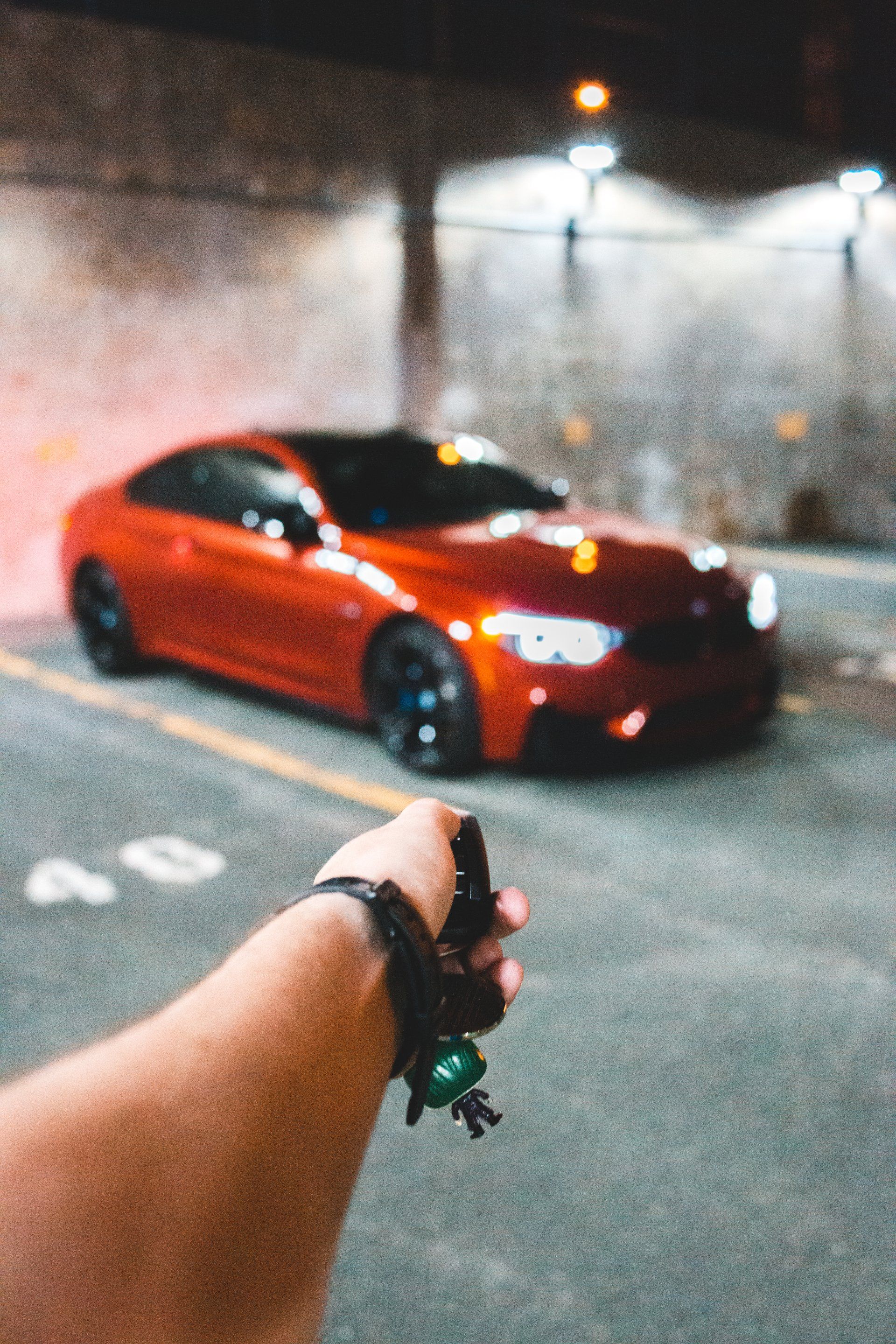 Hand pointing toward a red car parked in a dimly lit garage.